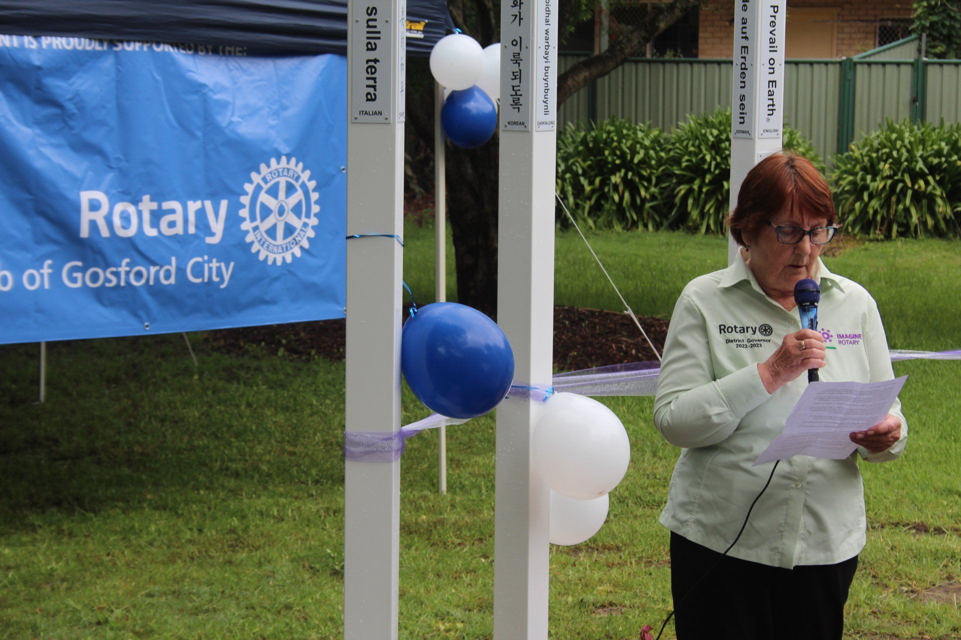 A woman stands in front of a sign that says rotary