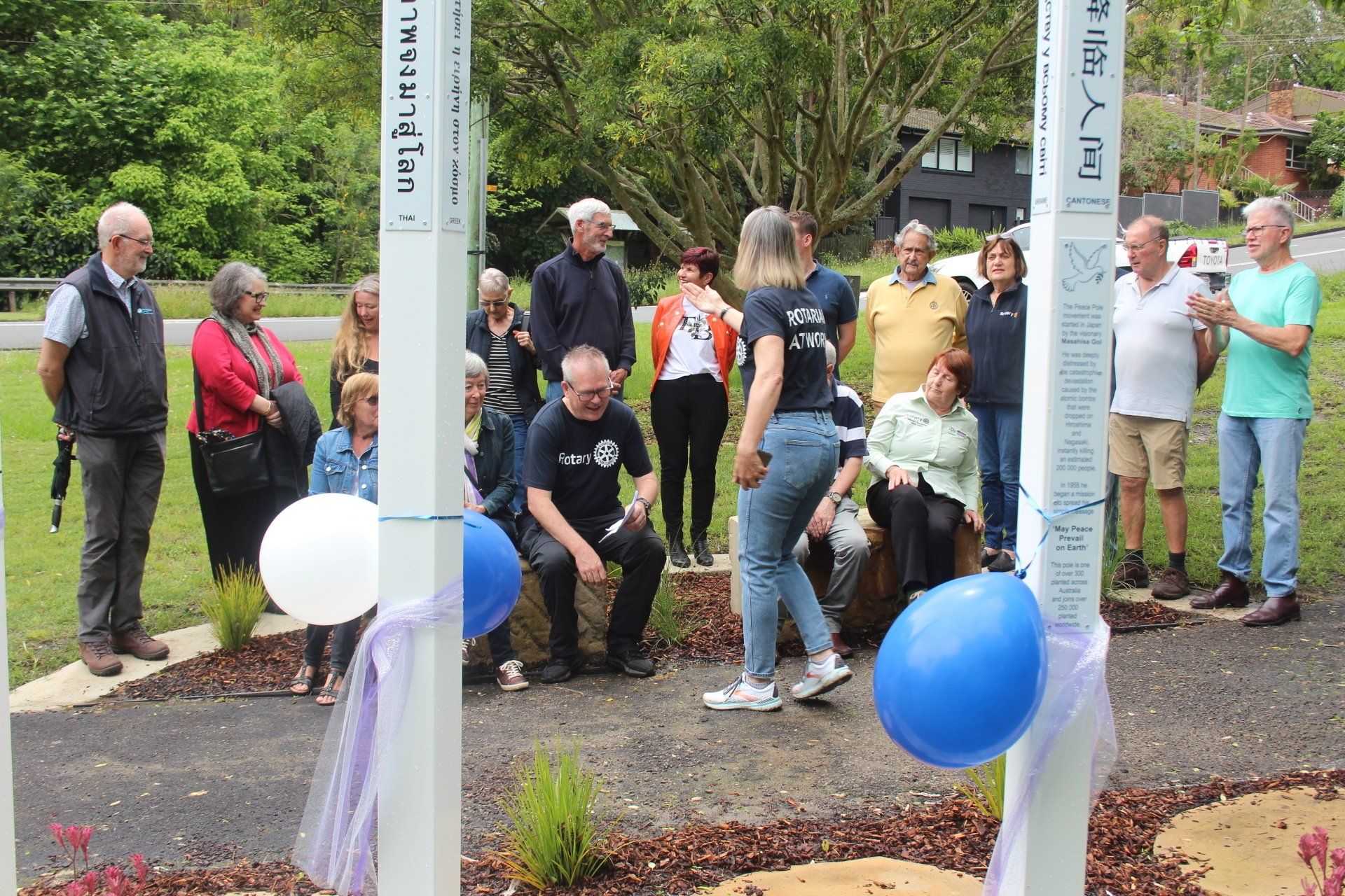 A group of people are standing around a pole with balloons on it.