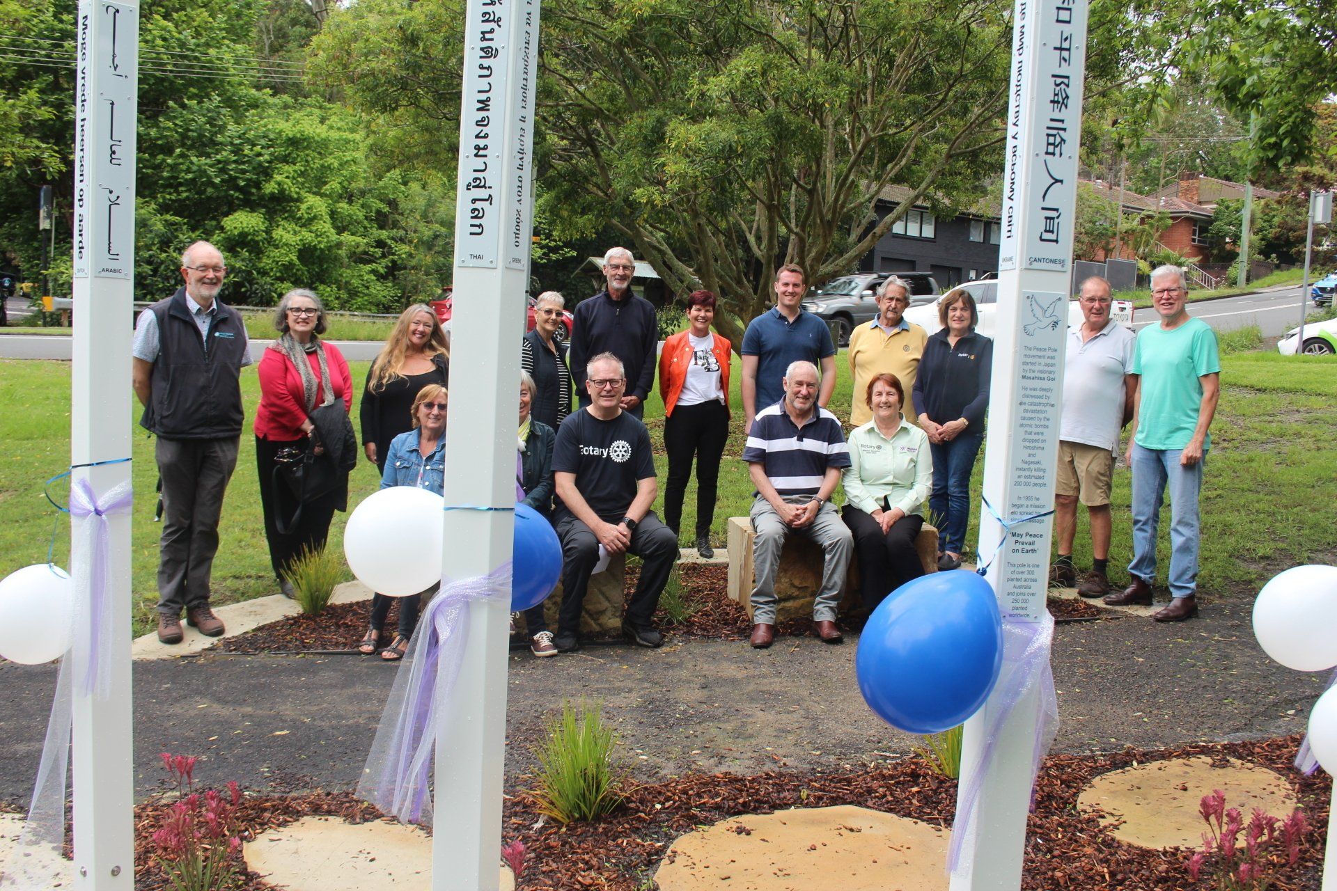 A group of people are posing for a picture in a park with balloons