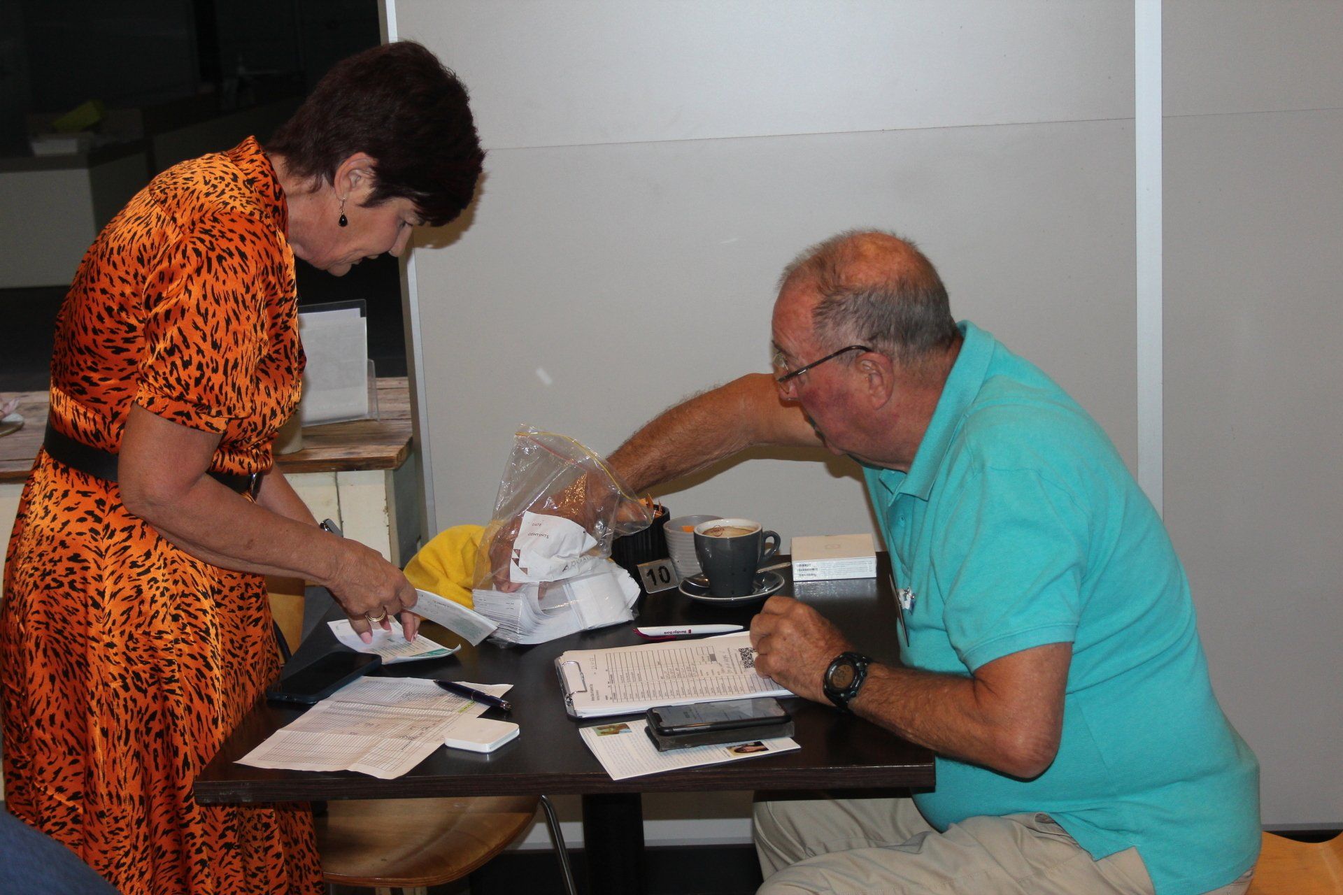 A man and a woman are sitting at a table with papers on it.