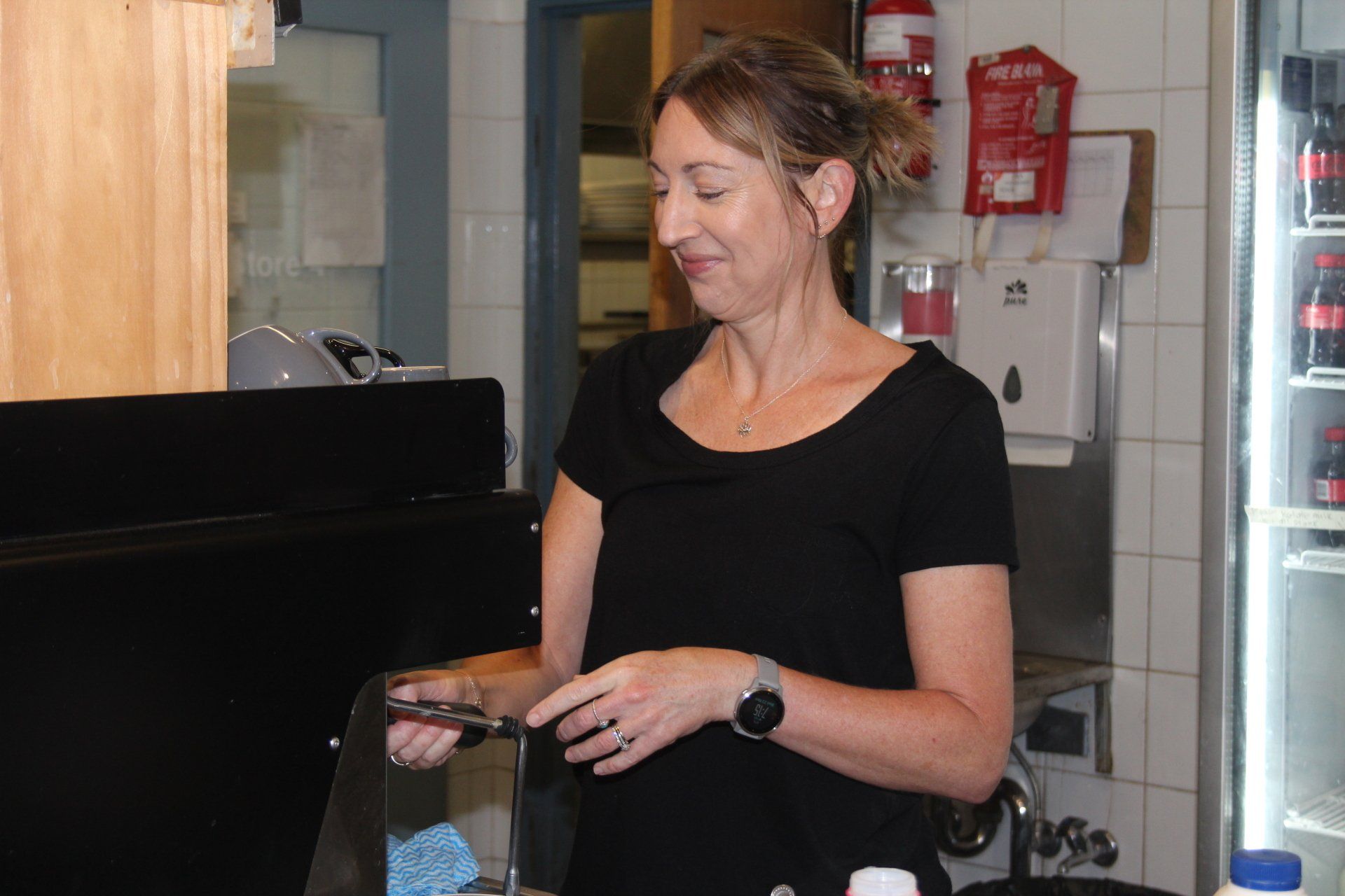 A woman in a black shirt is standing in a kitchen