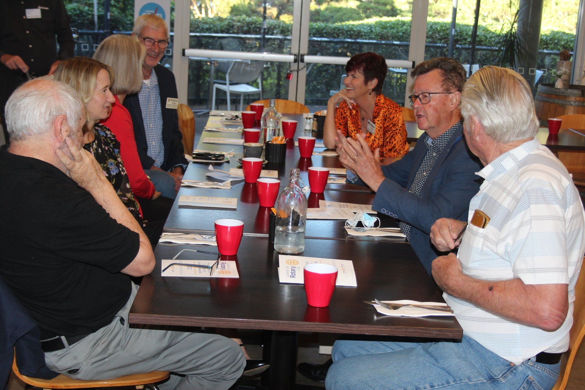 A group of people are sitting around a table with red cups on it