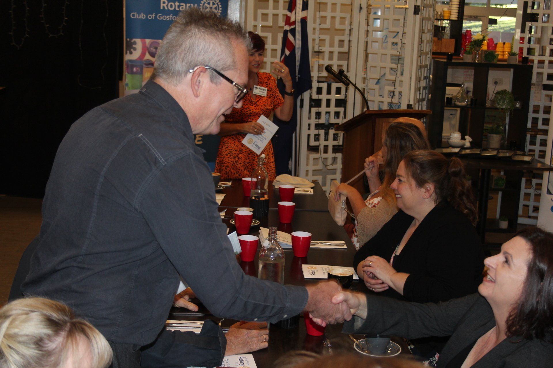 A man shakes hands with a woman at a table
