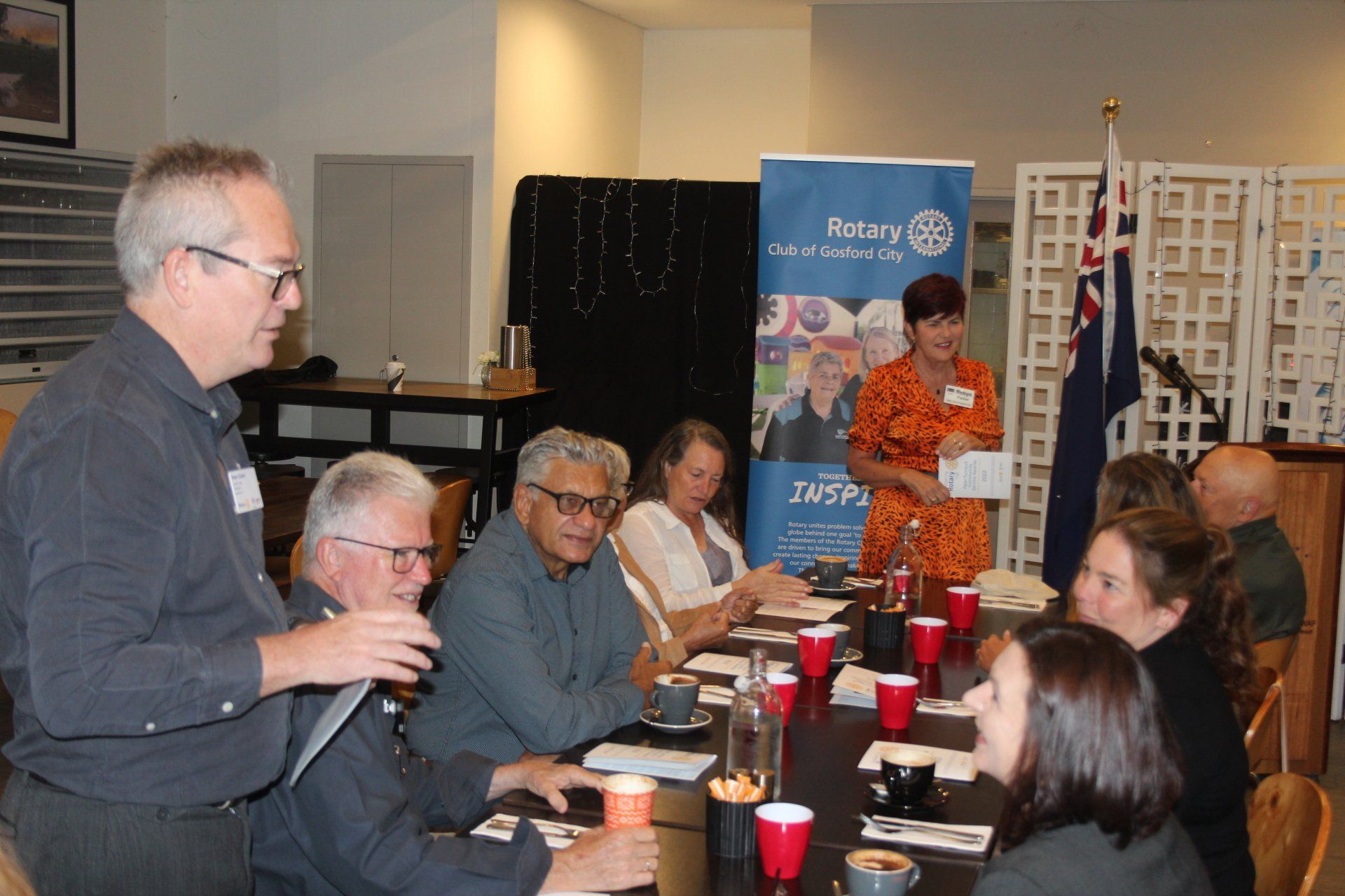 A man is giving a presentation to a group of people sitting around a table.