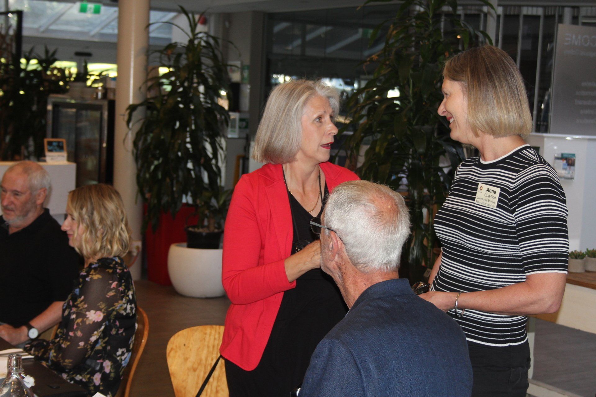 A group of people are sitting at a table talking to each other.