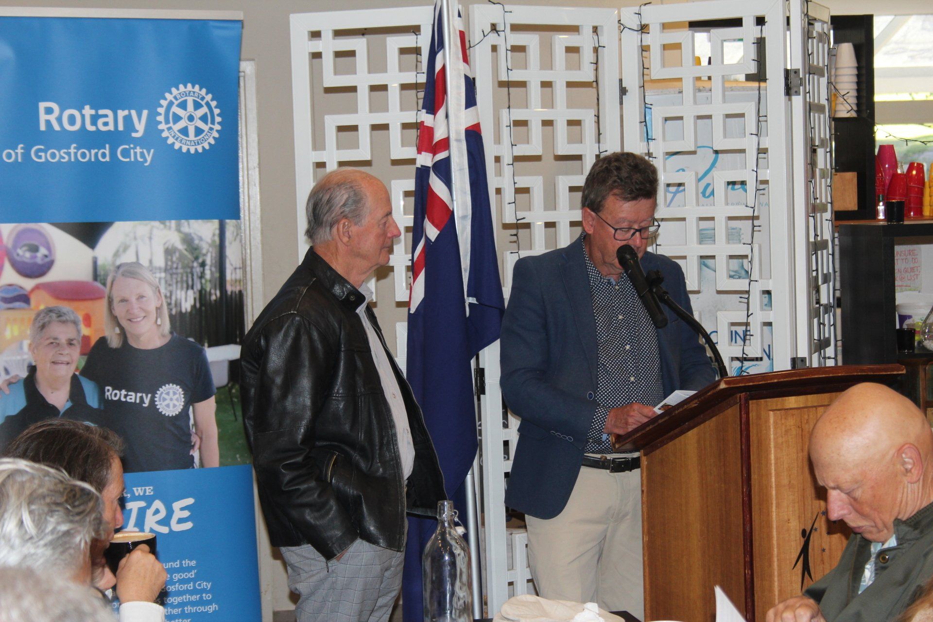 A man stands at a podium in front of a sign that says rotary