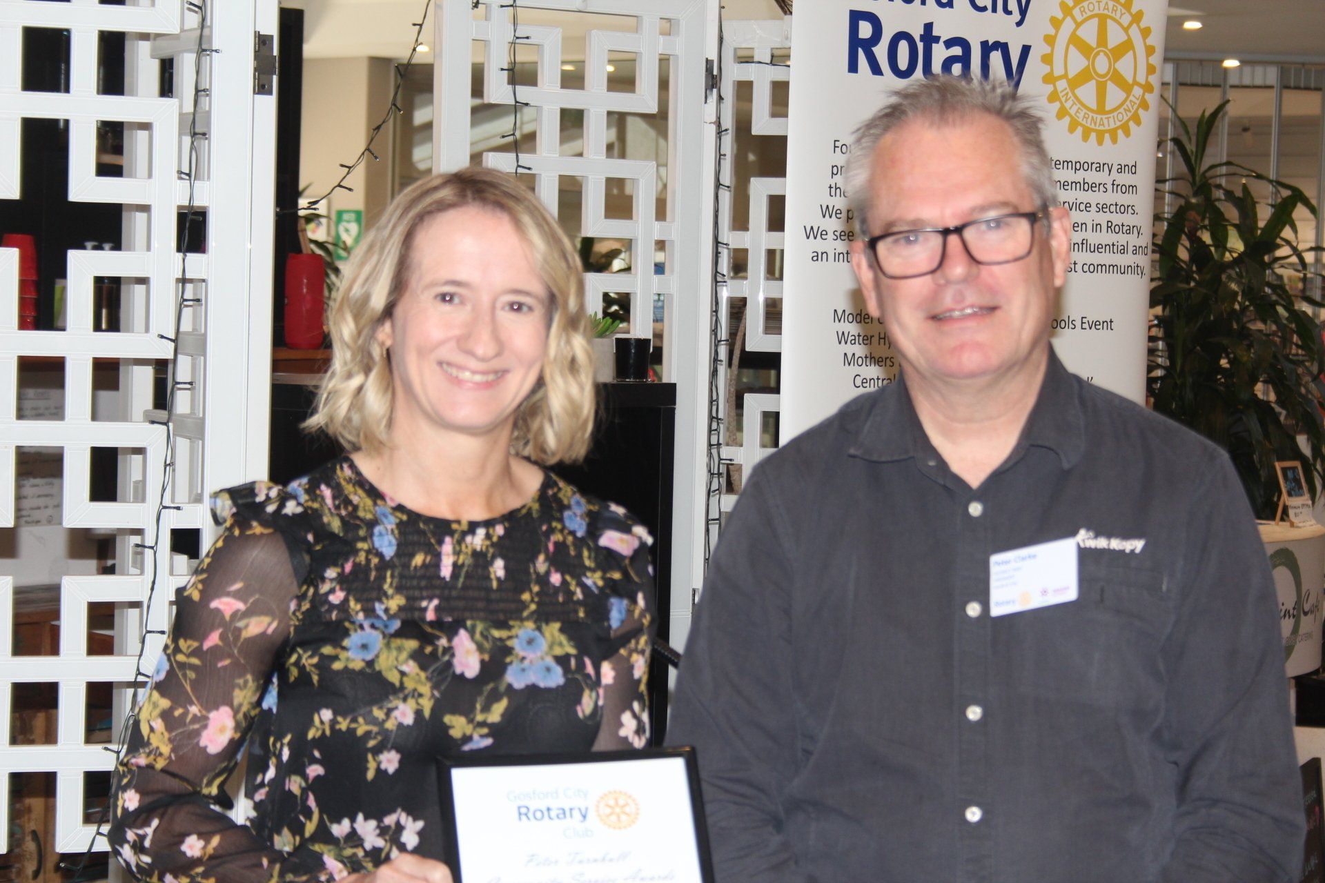 A man and a woman are standing next to each other in front of a rotary sign.