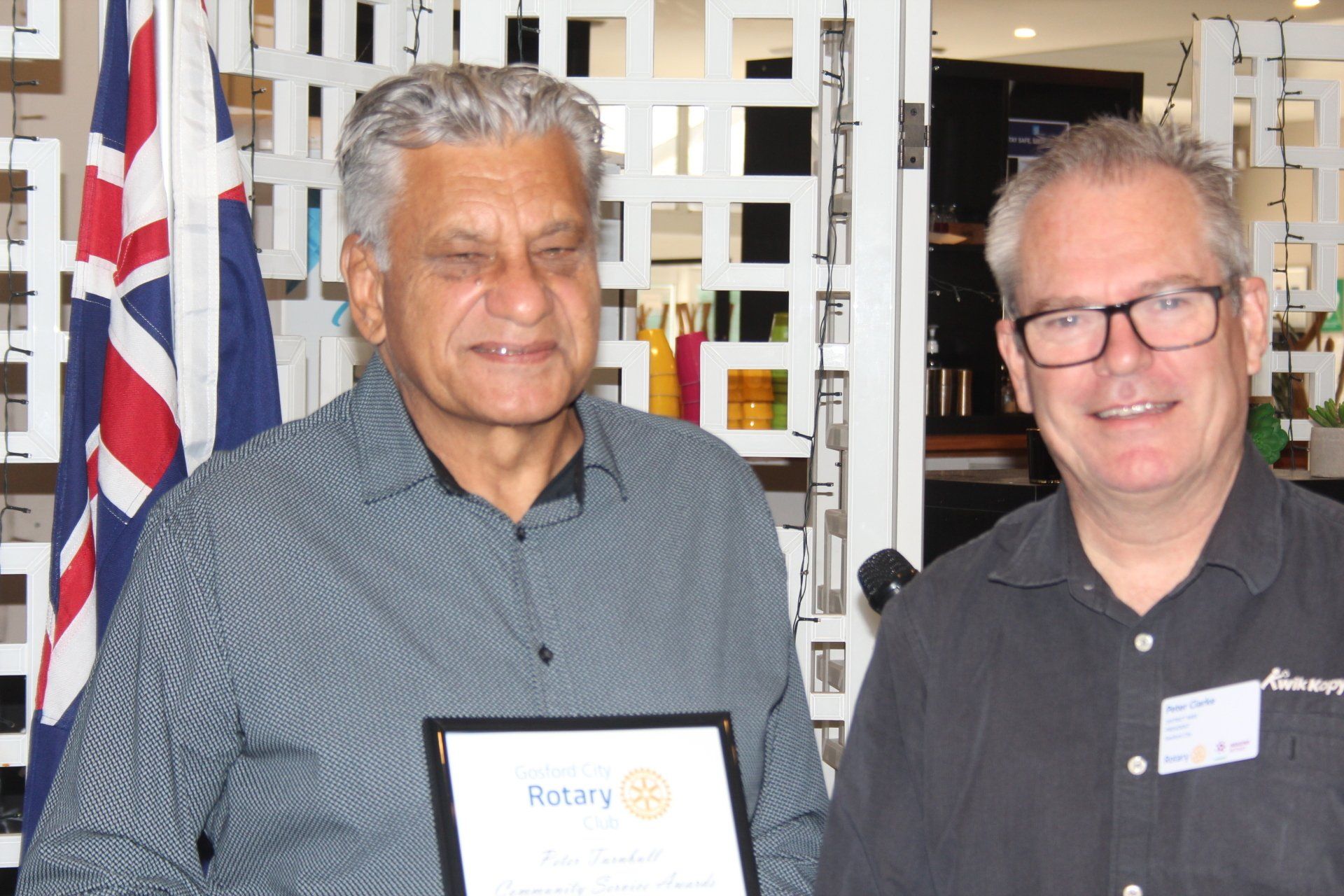 Two men are standing next to each other holding a rotary certificate
