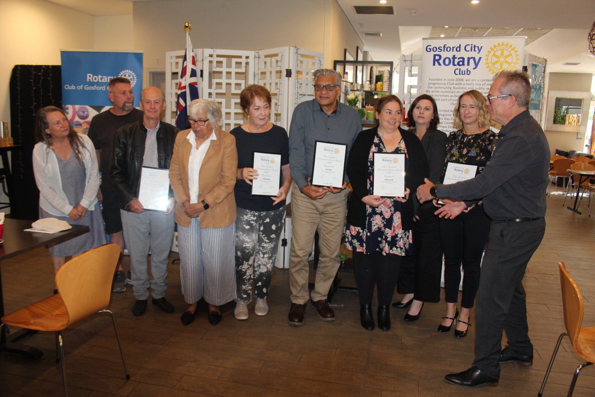 A group of people standing next to each other in a room holding certificates.