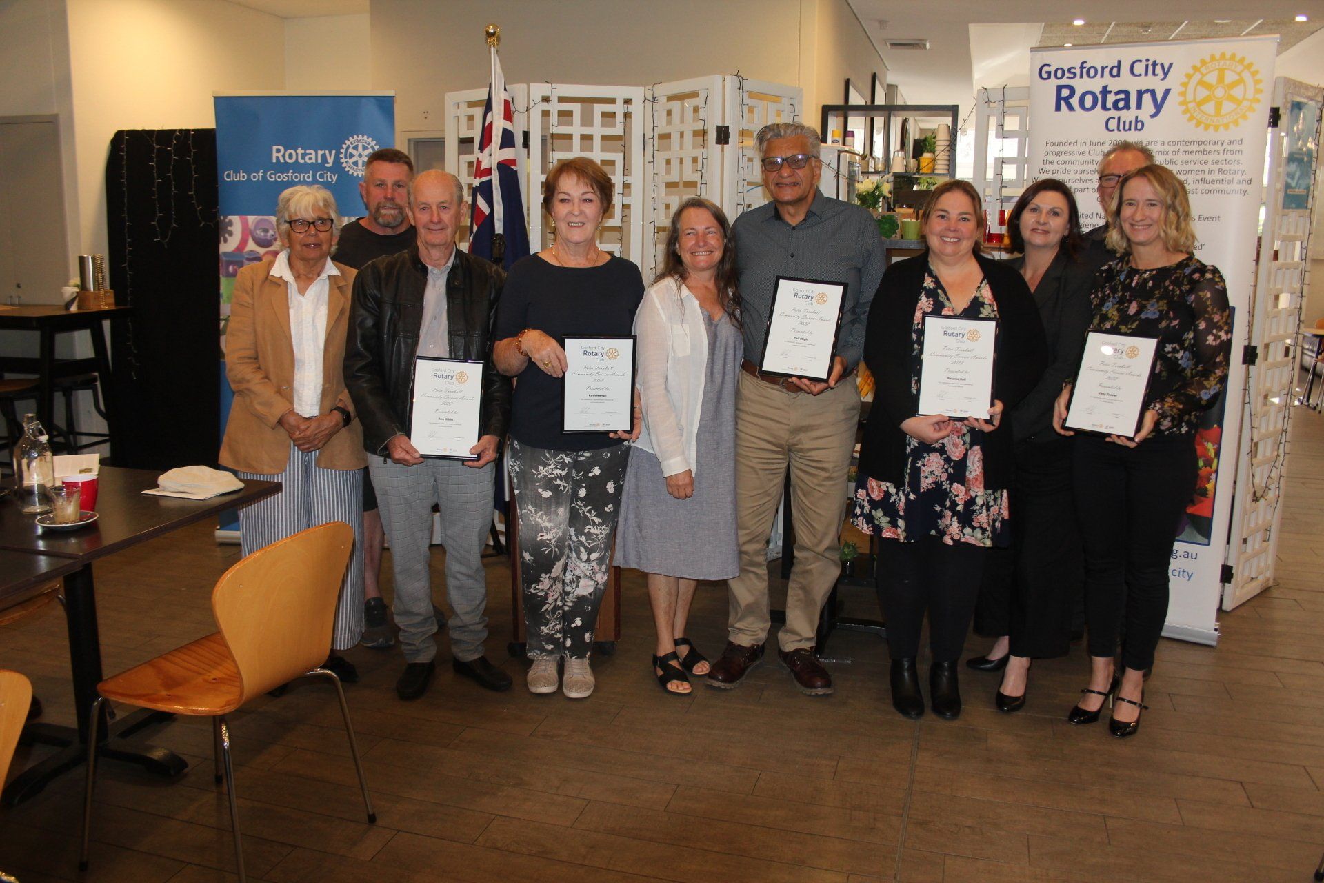 A group of people are standing next to each other in a room holding certificates.