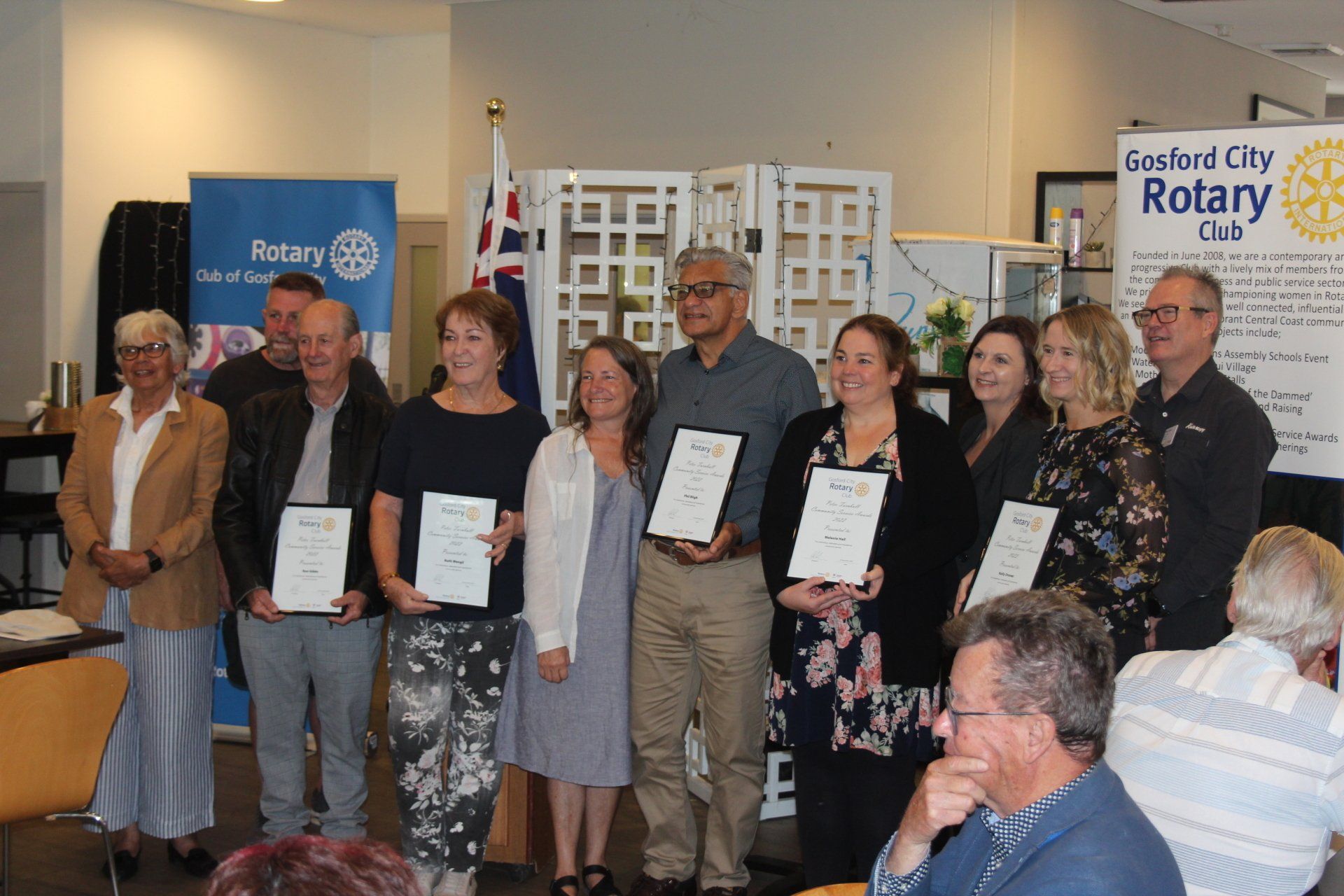 A group of people are posing for a picture in front of a sign that says rotary club