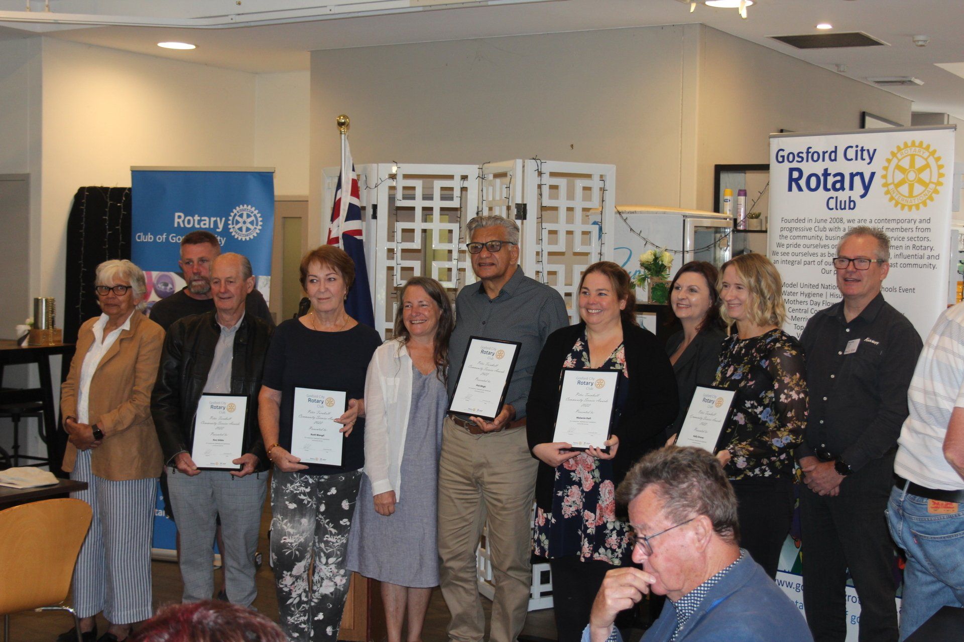 A group of people are standing in a room holding certificates.