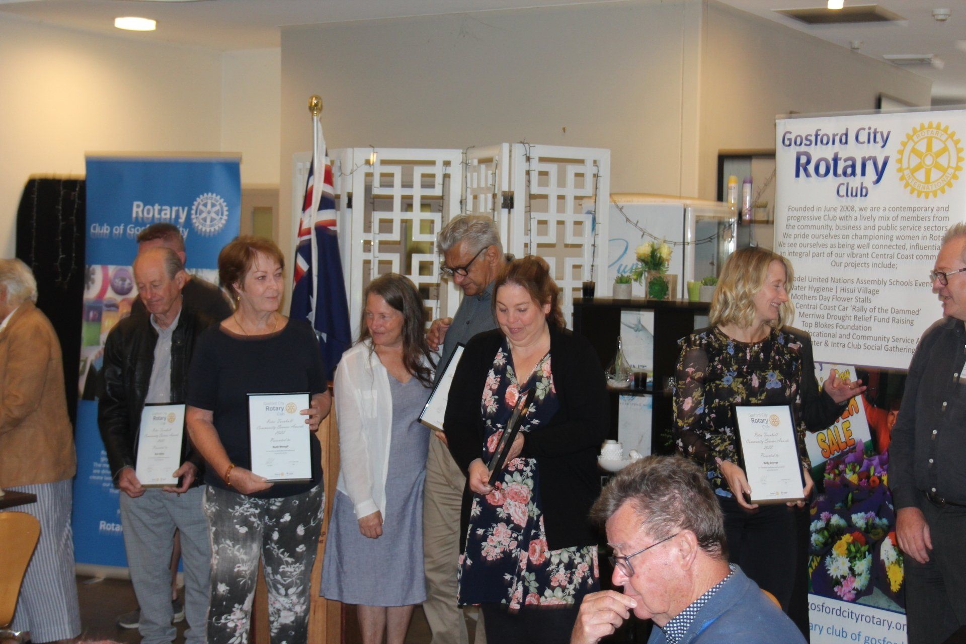 A group of people are standing in a room holding certificates.