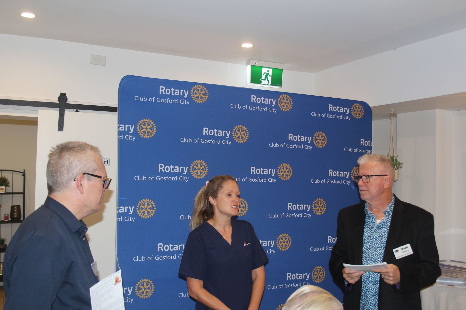 A group of people standing in front of a wall that says rotary