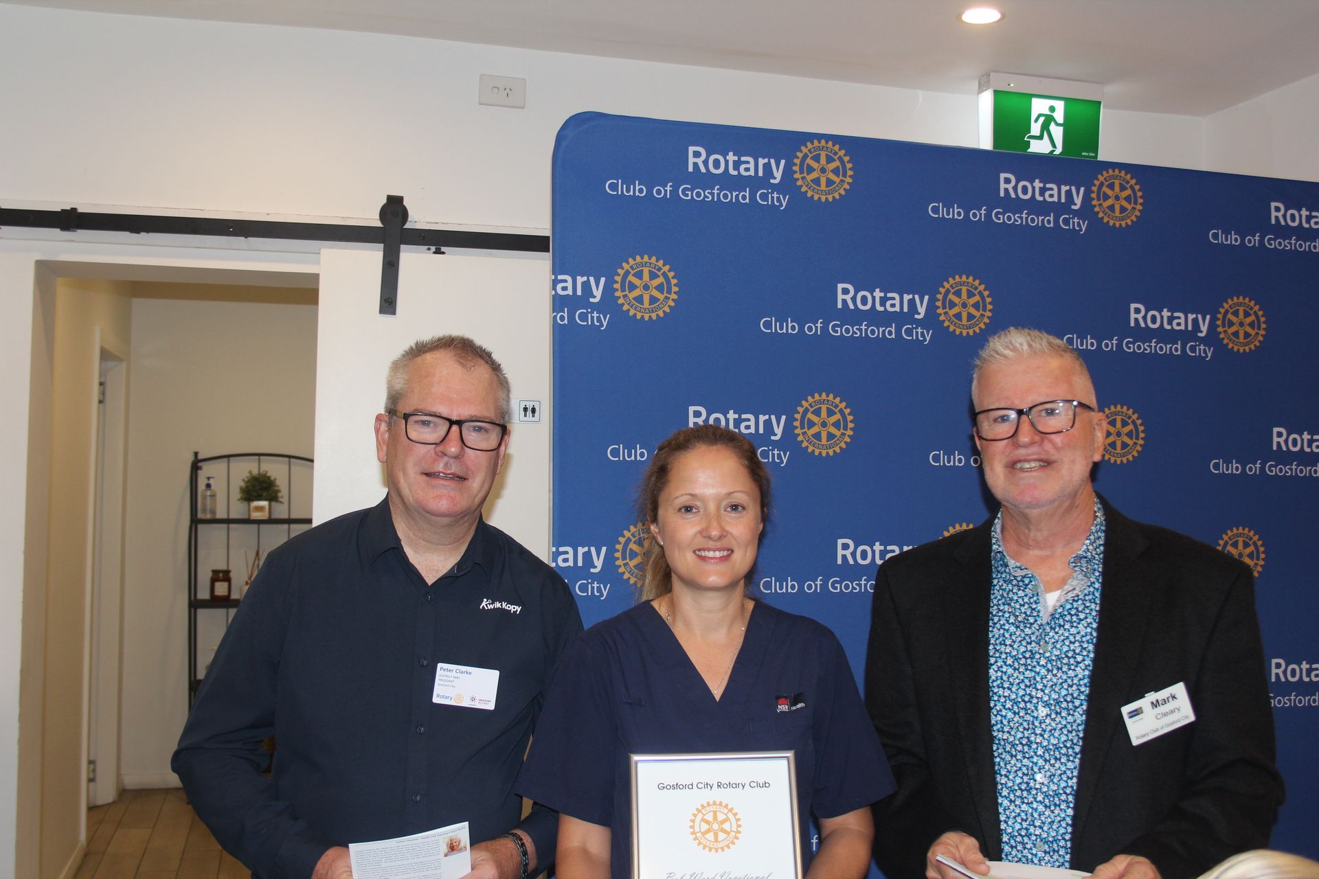 Three people are standing next to each other in front of a blue backdrop.