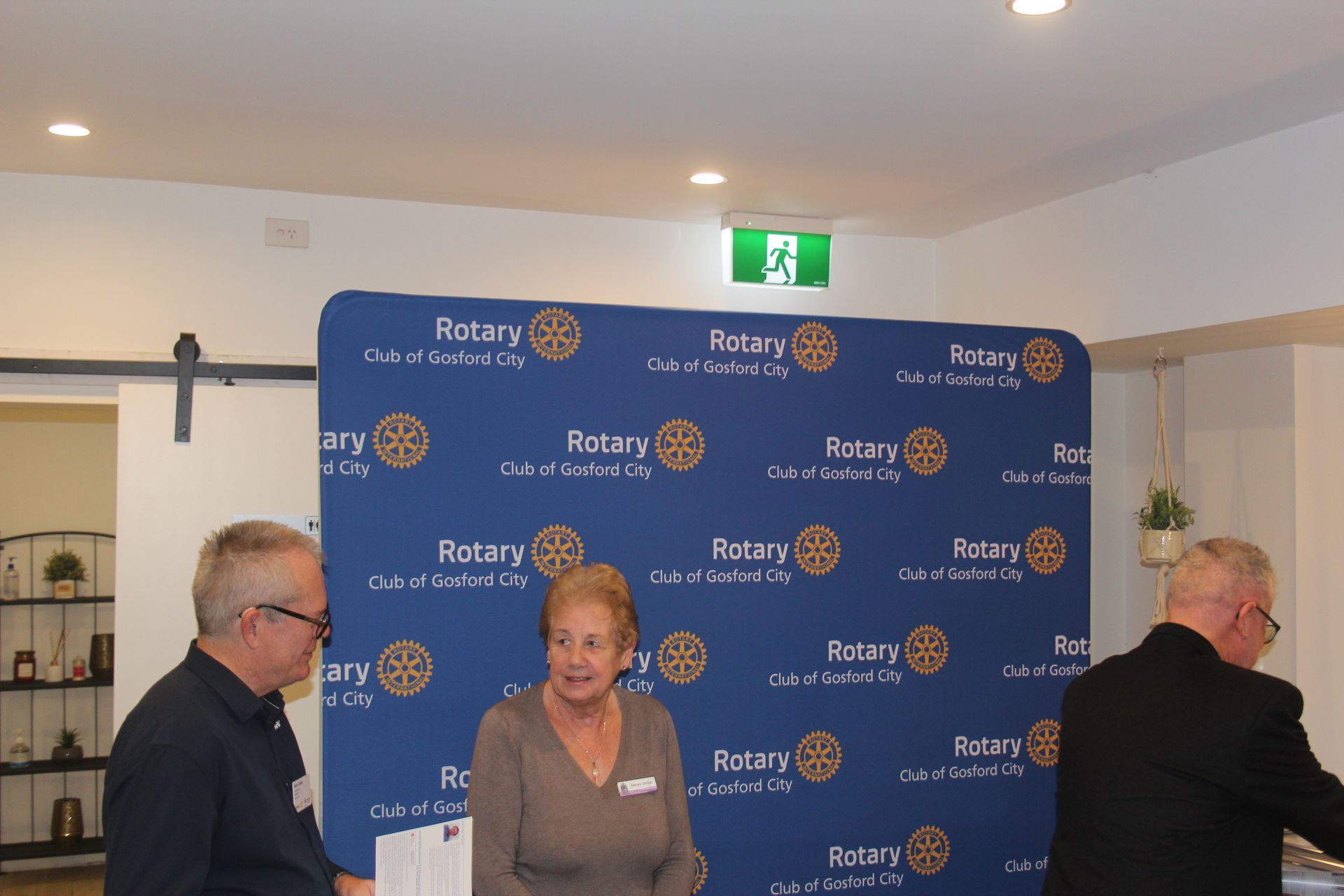 A group of people standing in front of a wall that says rotary