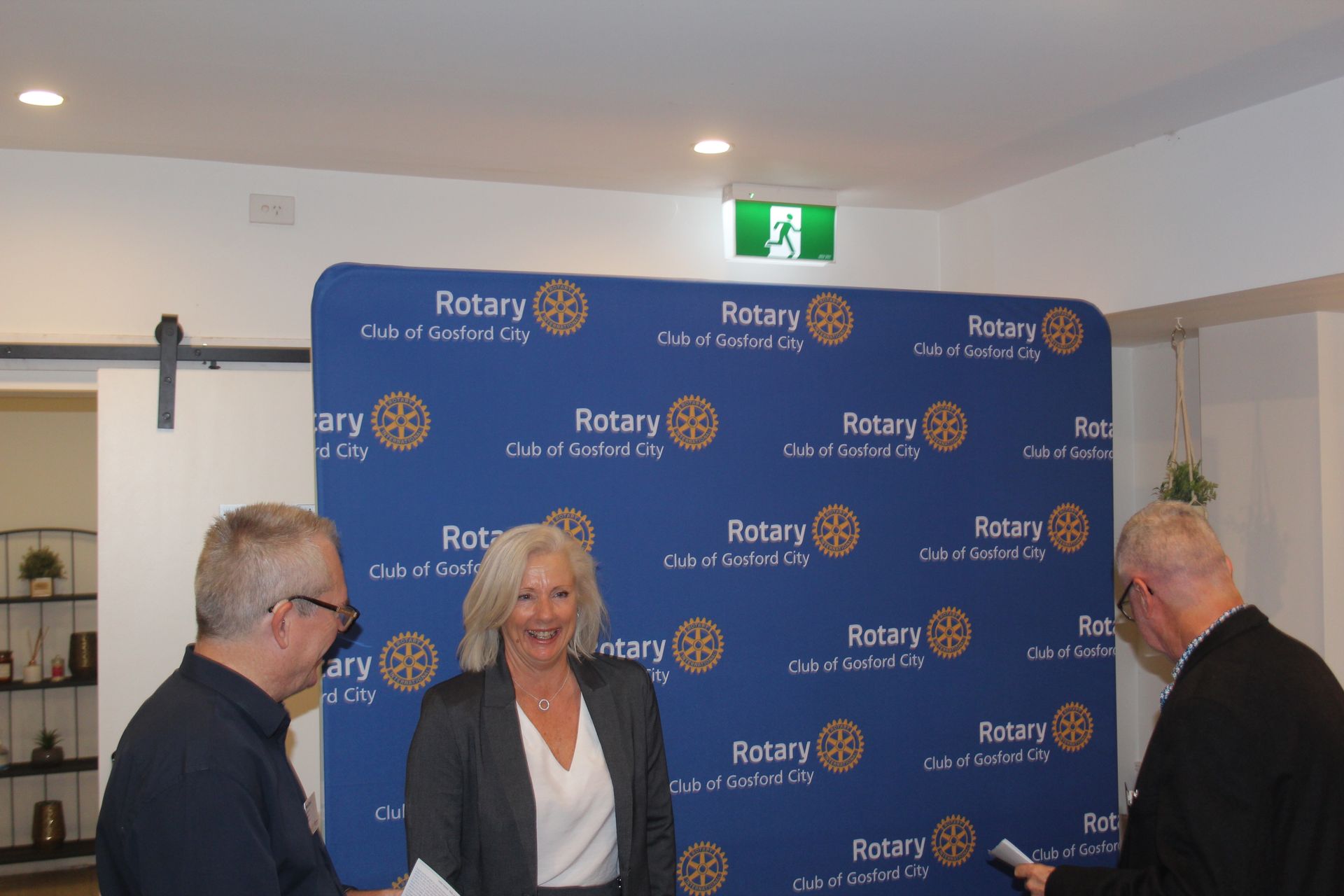 A group of people are standing in front of a wall that says rotary