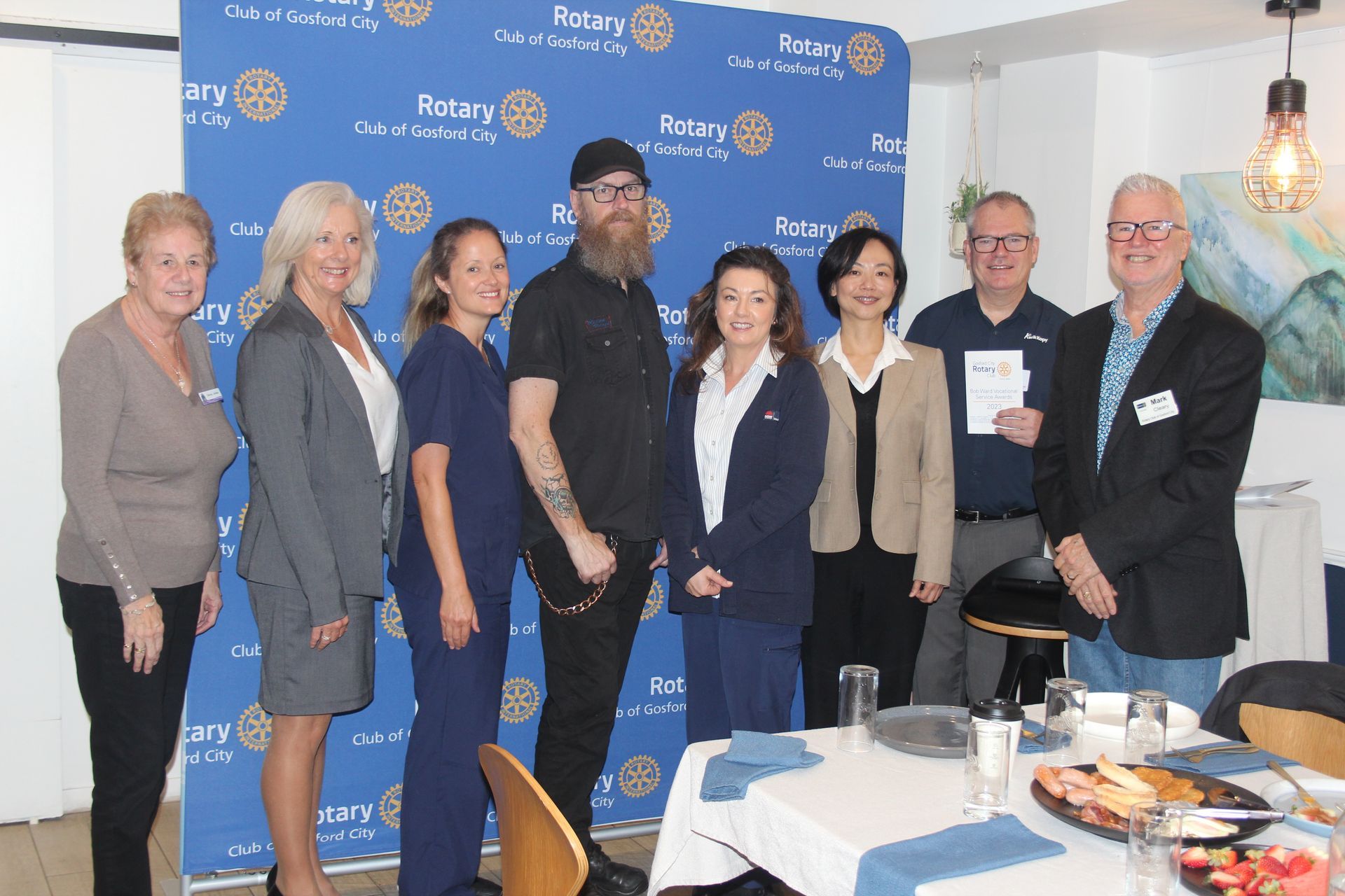 A group of people are posing for a picture in front of a table.