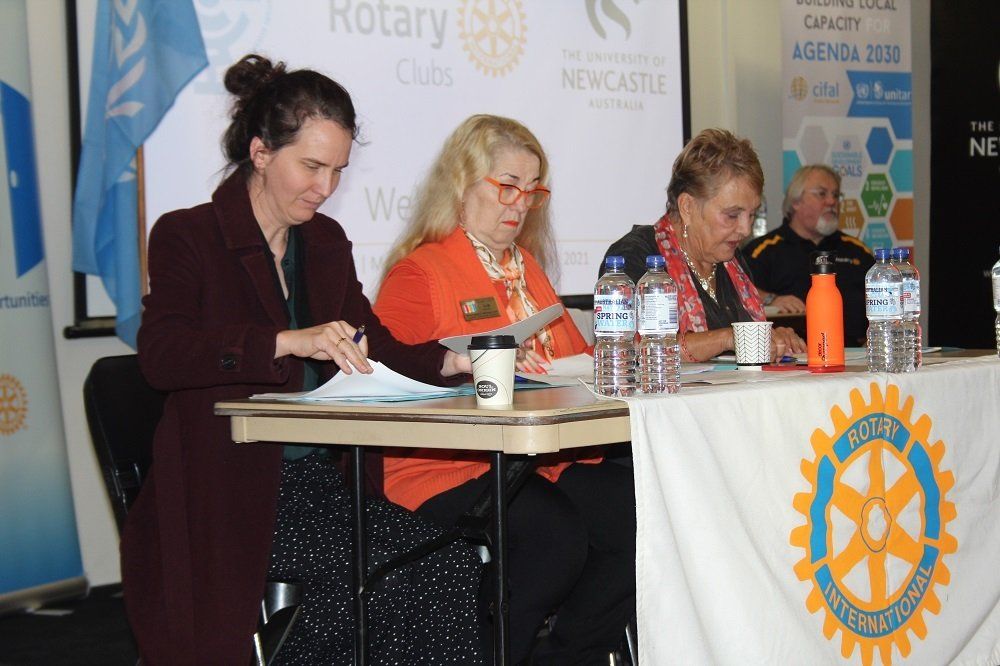 A group of women are sitting at a table with a rotary logo on it