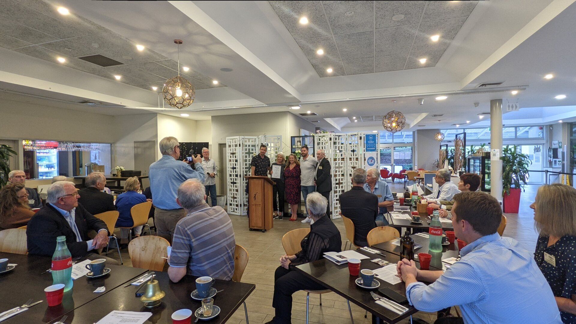 A group of people are sitting at tables in a large room.