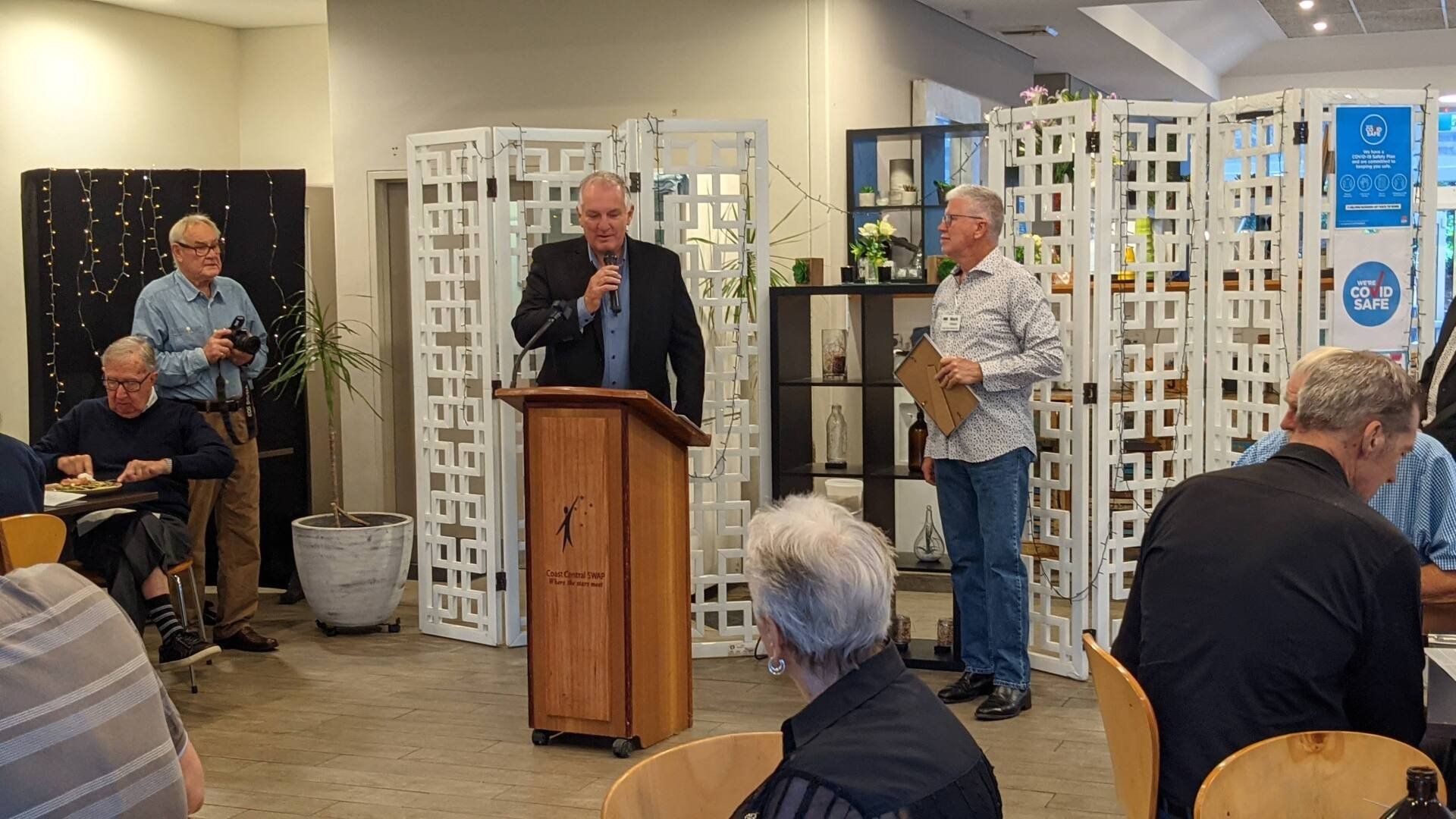 A man is standing at a podium giving a speech to a group of people.