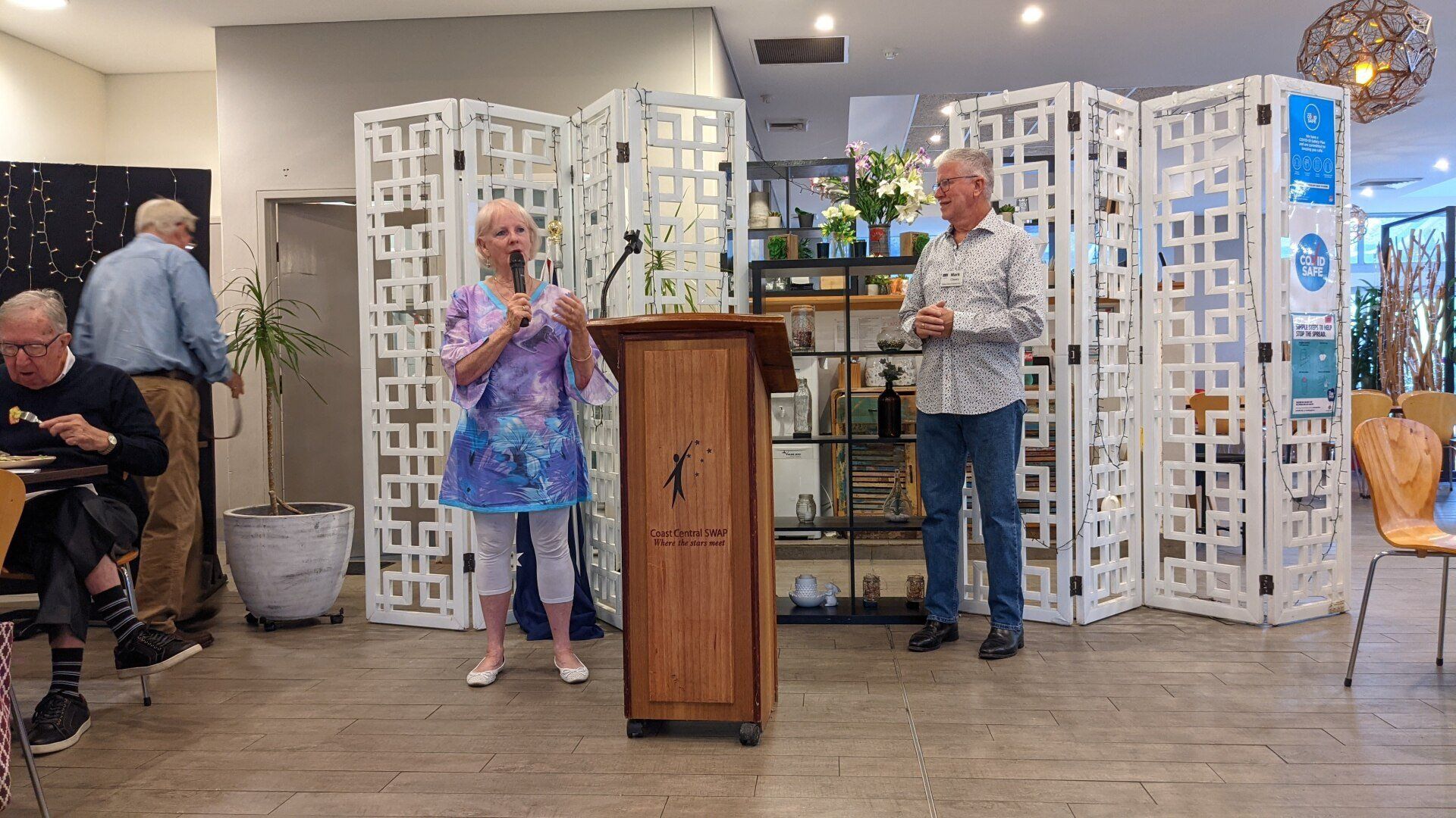 A man and a woman are standing at a podium in a room.