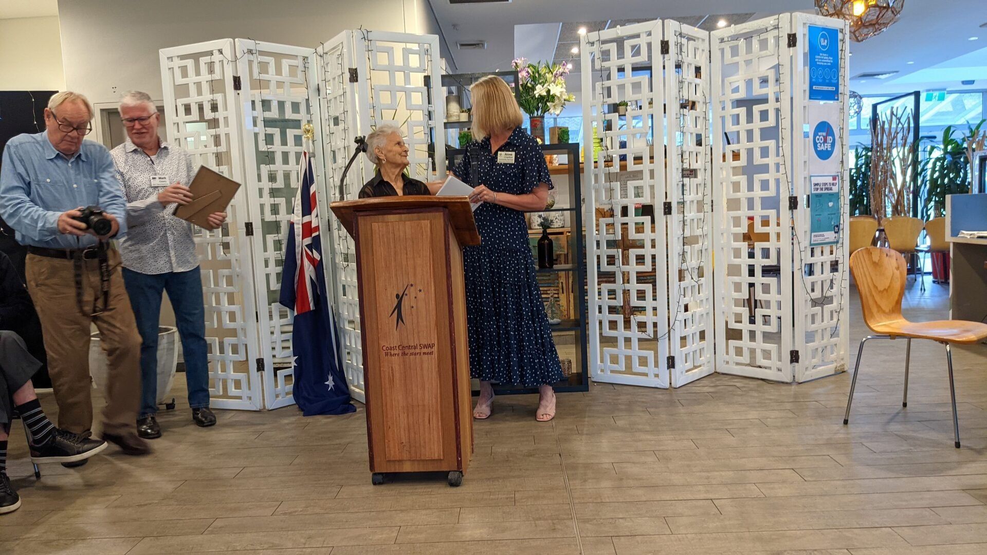 A group of people are standing around a podium in a room.