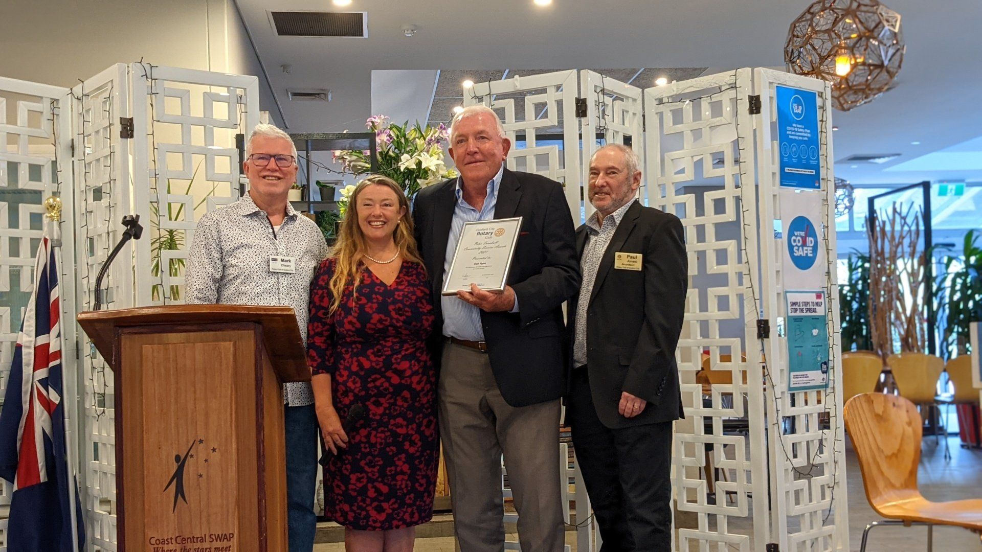 A group of people standing around a podium holding a certificate.