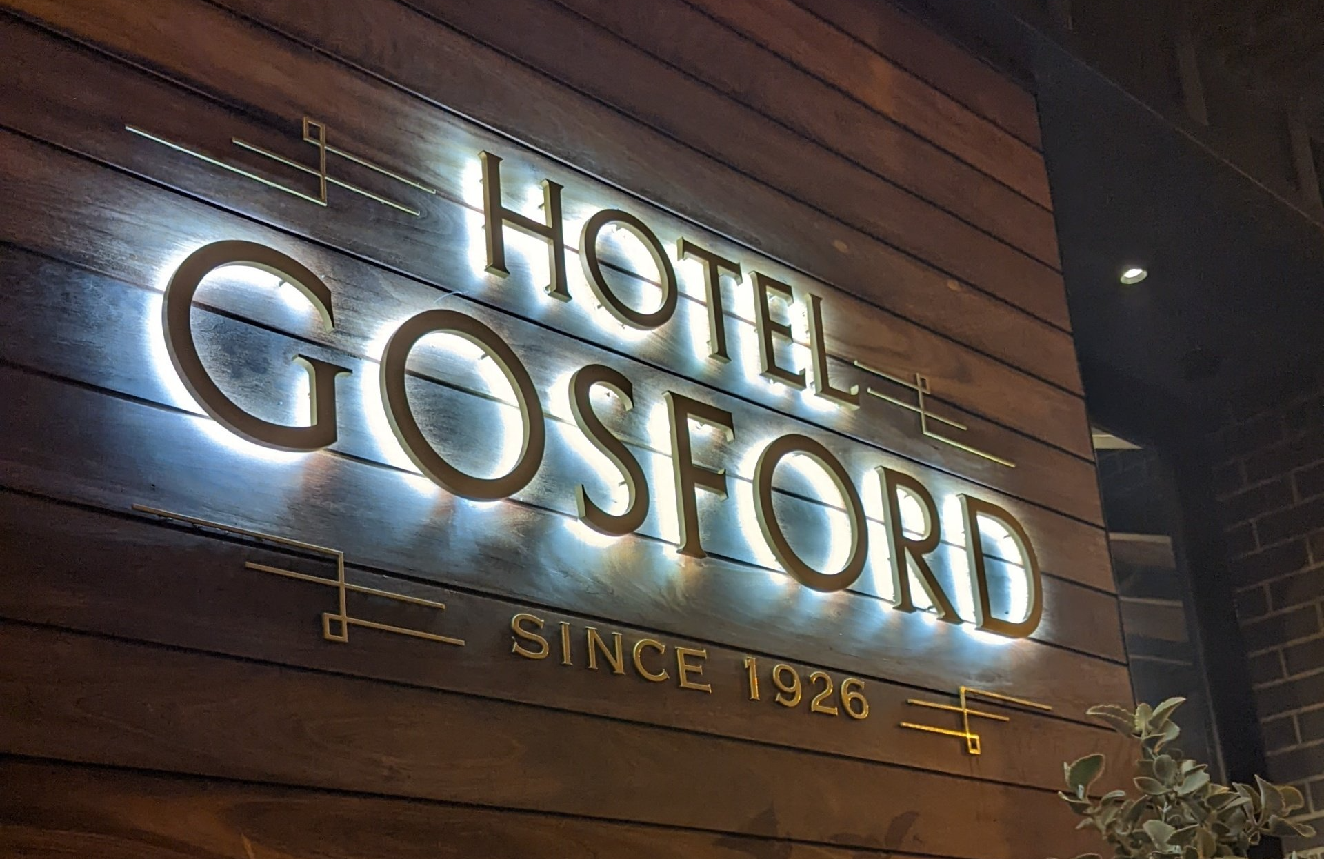 A sign for the hotel gosford is lit up at night