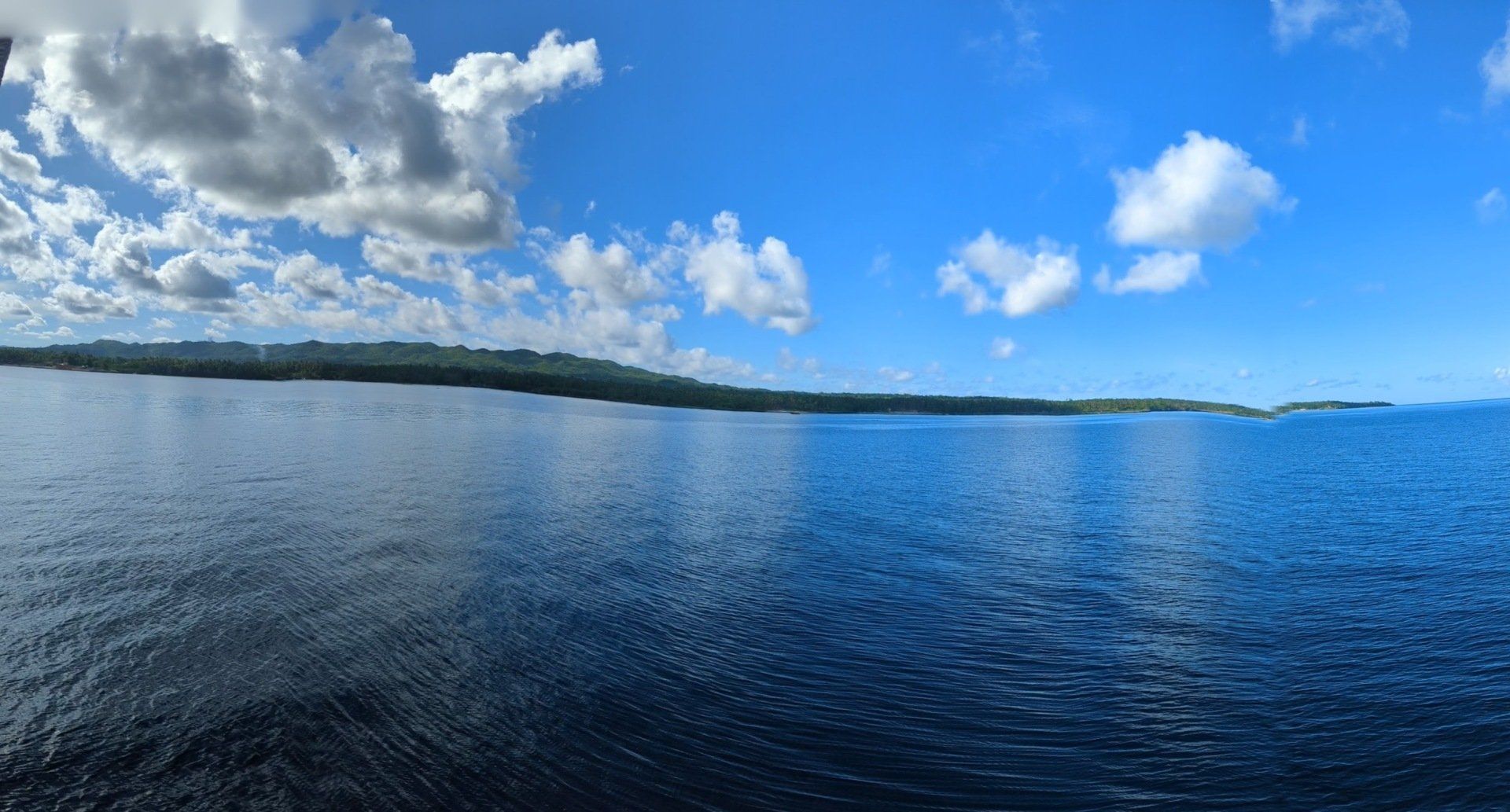 A large body of water with a blue sky and clouds in the background
