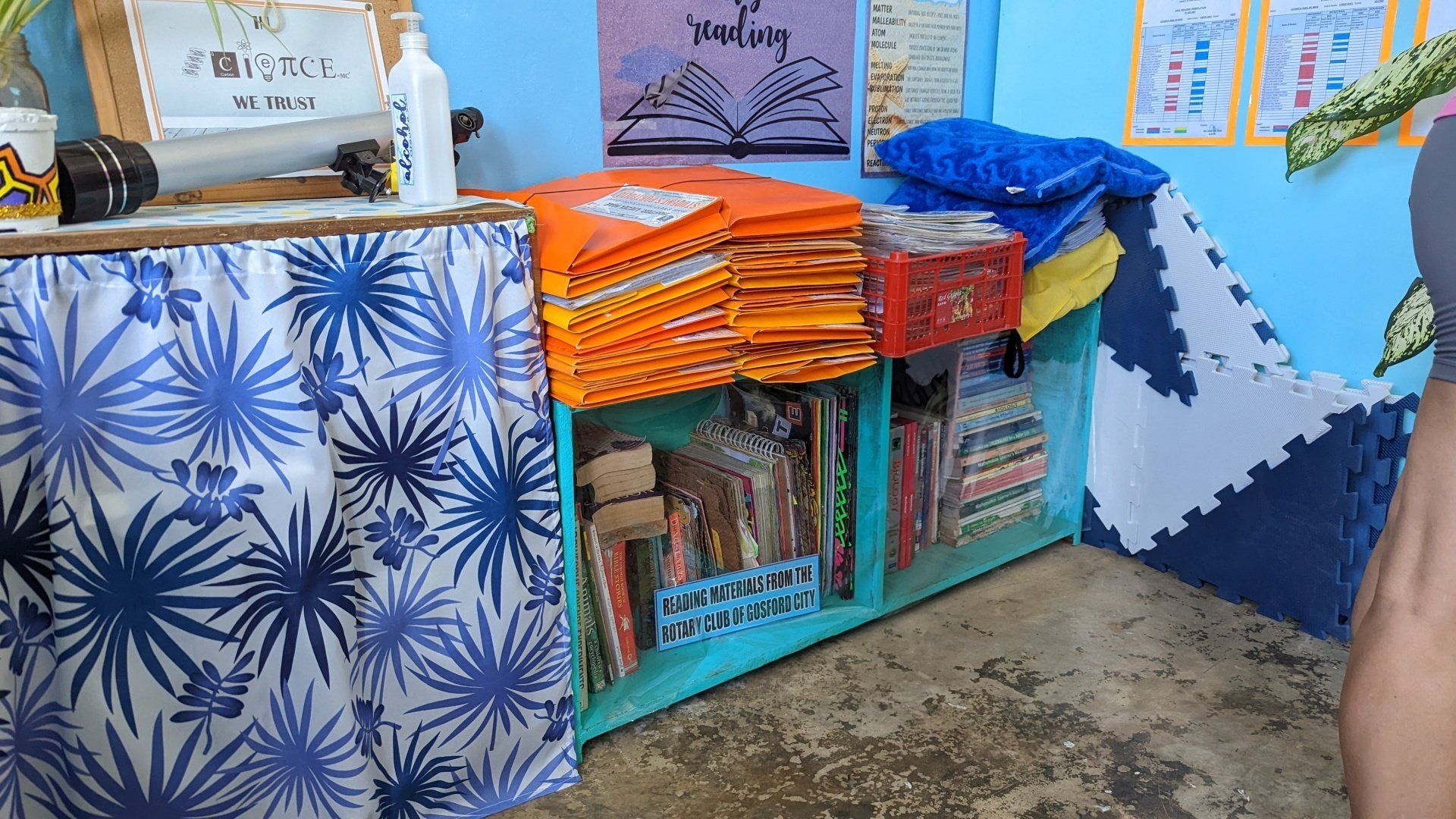 A person is standing in a room with a shelf full of books.
