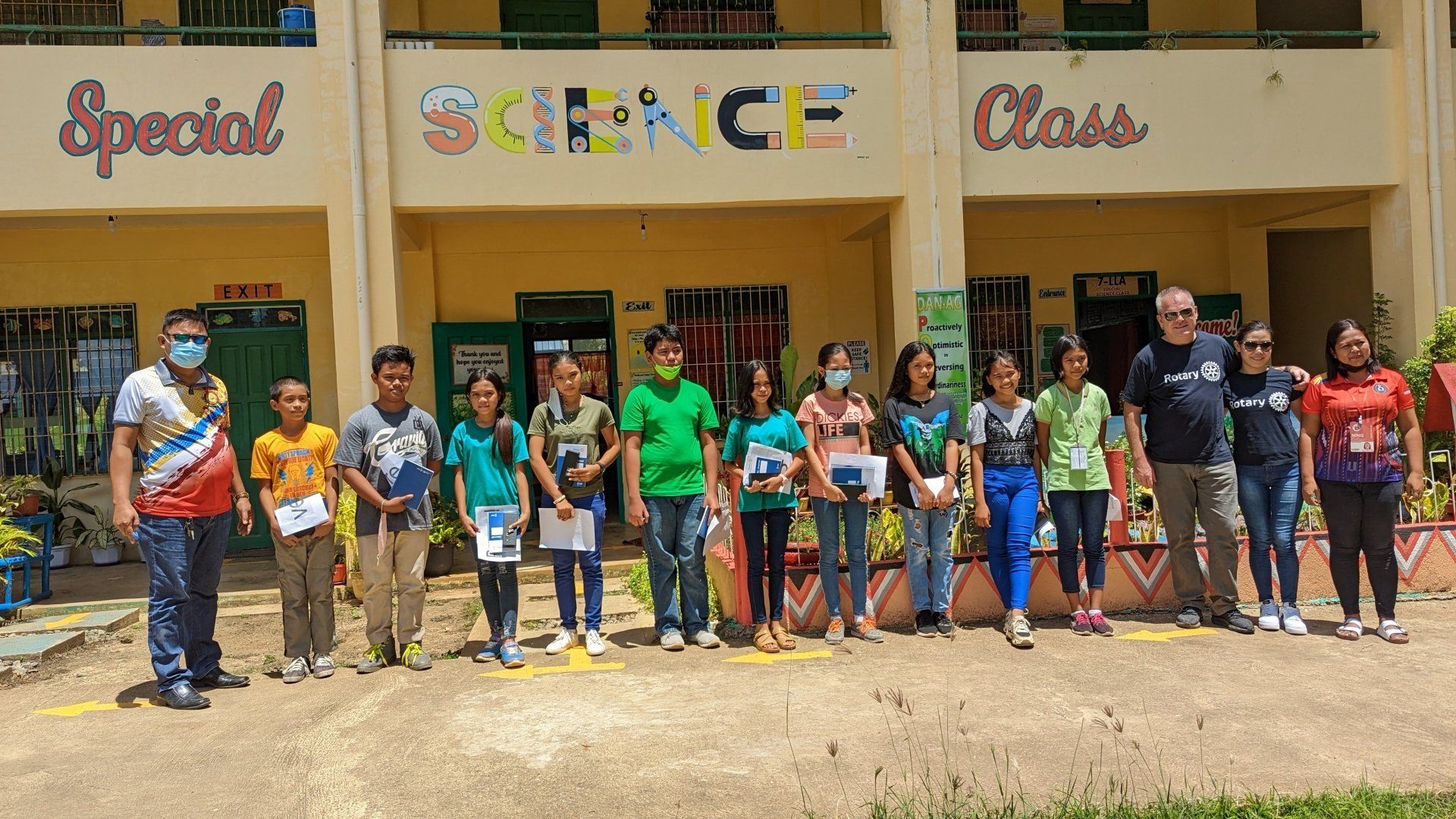 A group of people are standing in front of a building that says science class.