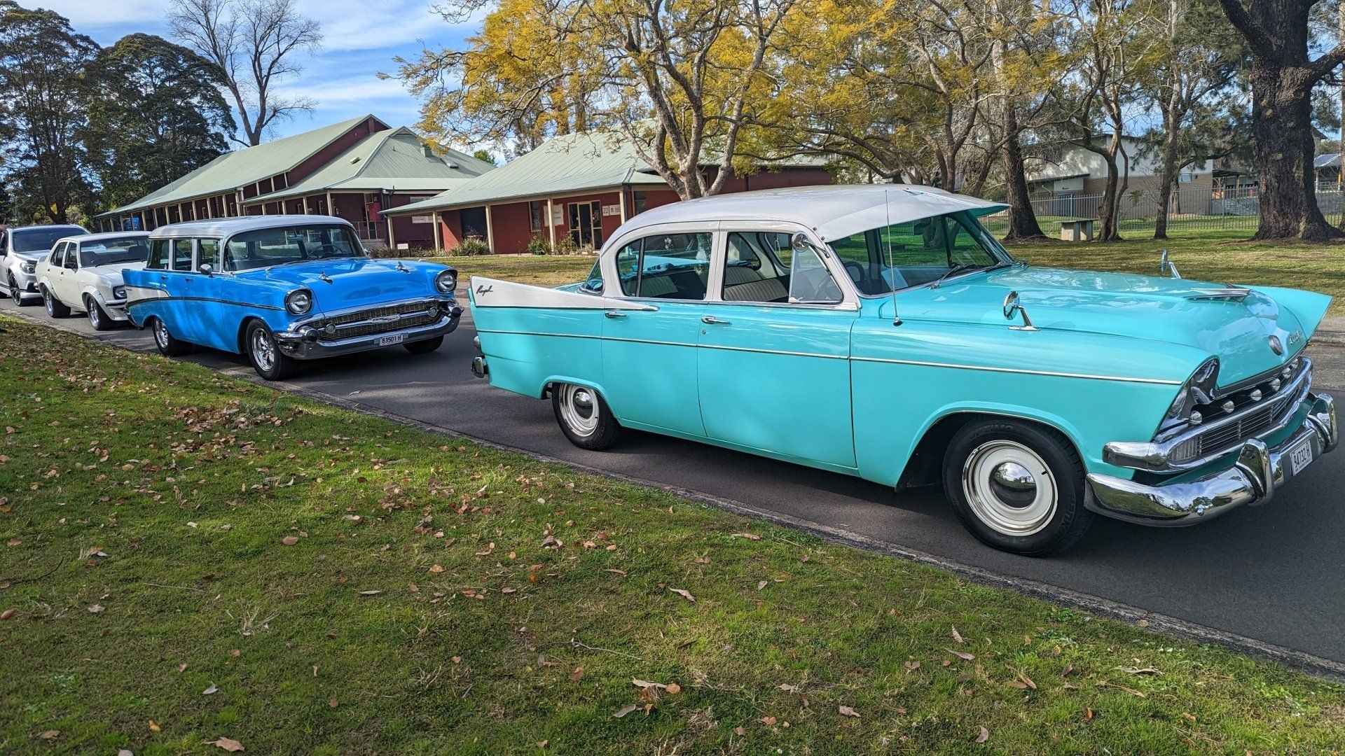Two old cars are parked next to each other on the side of the road.