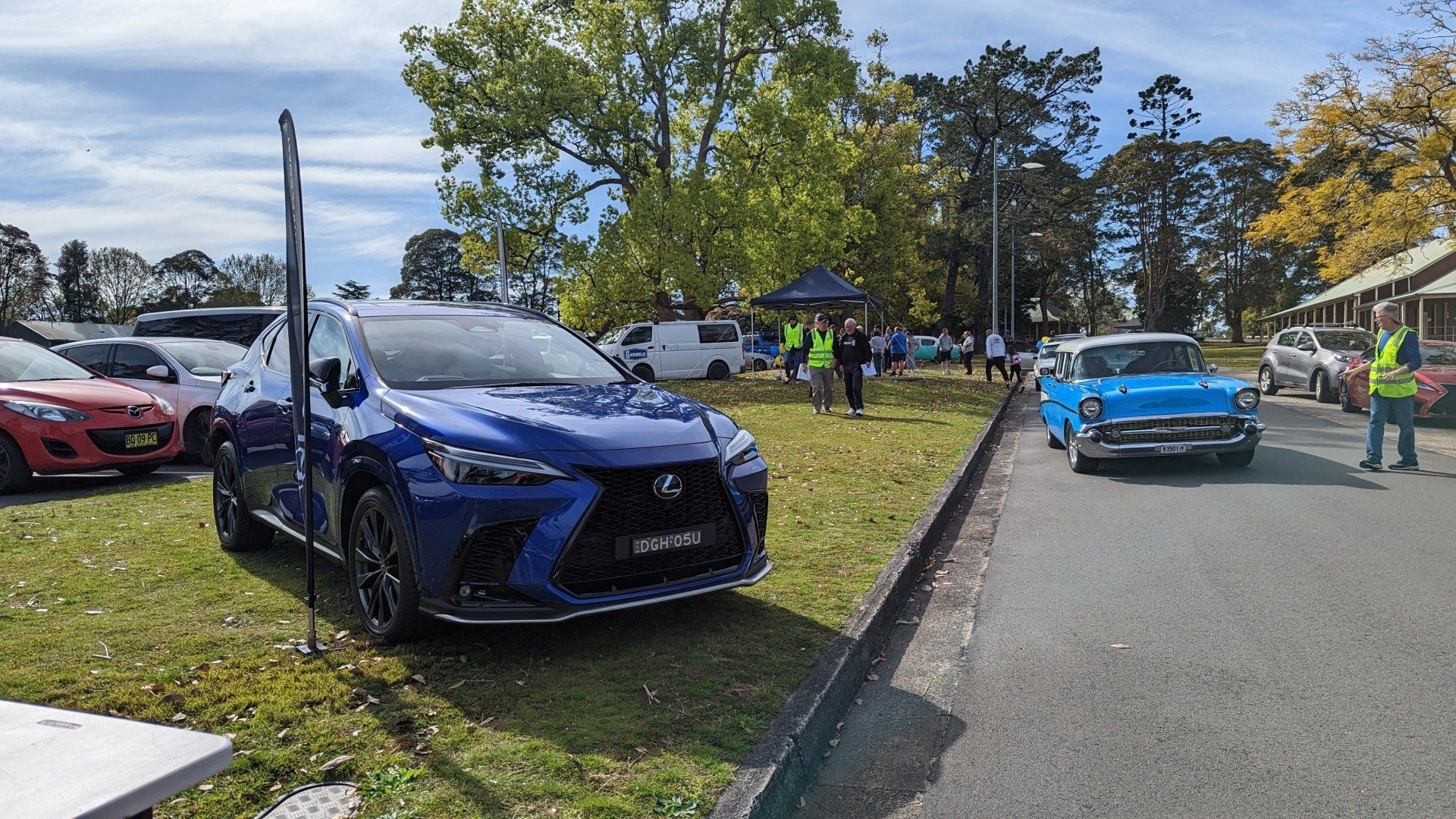 A blue car is parked on the side of the road next to a grassy field.