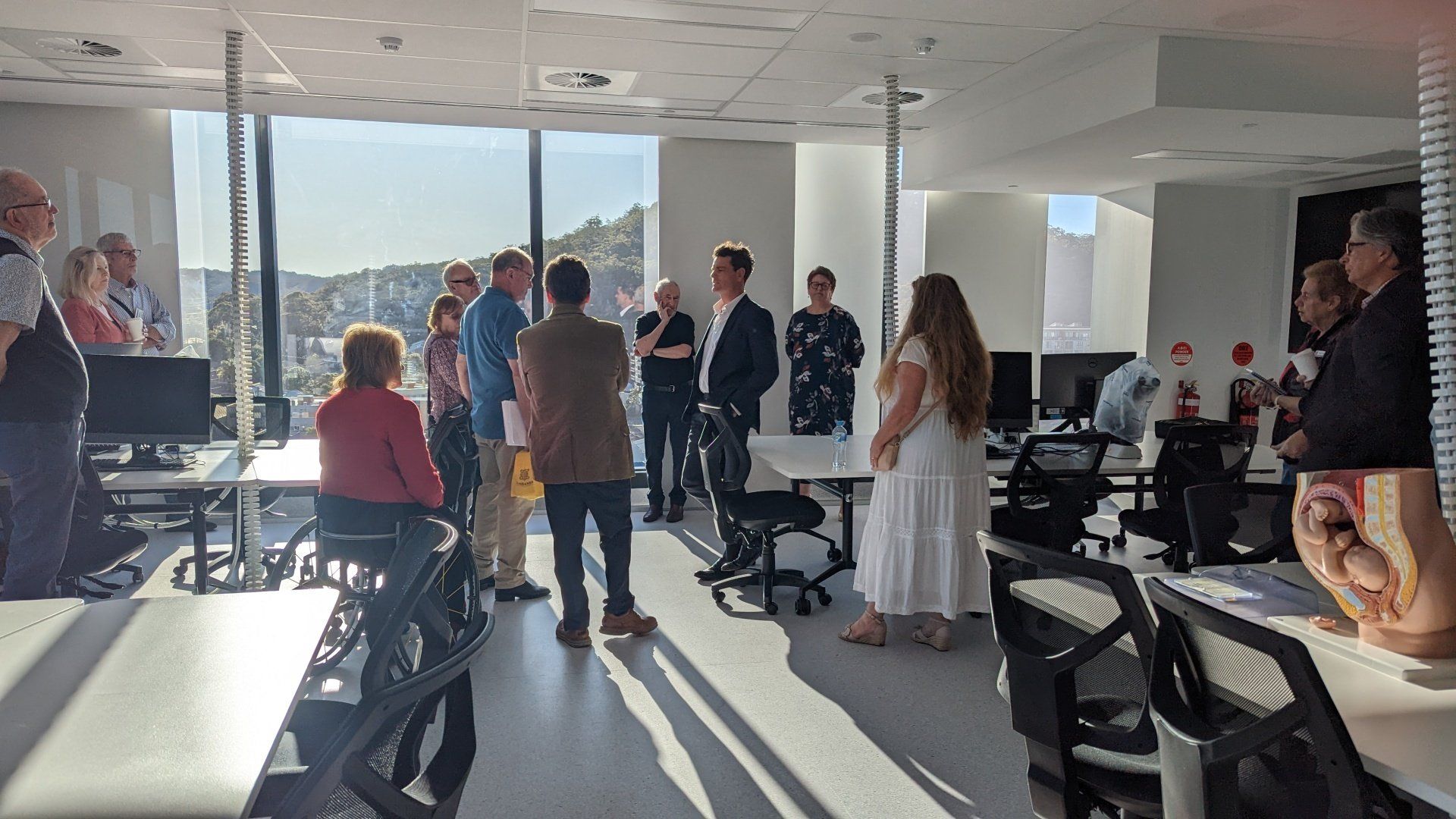 A group of people are standing in a room with tables and chairs.