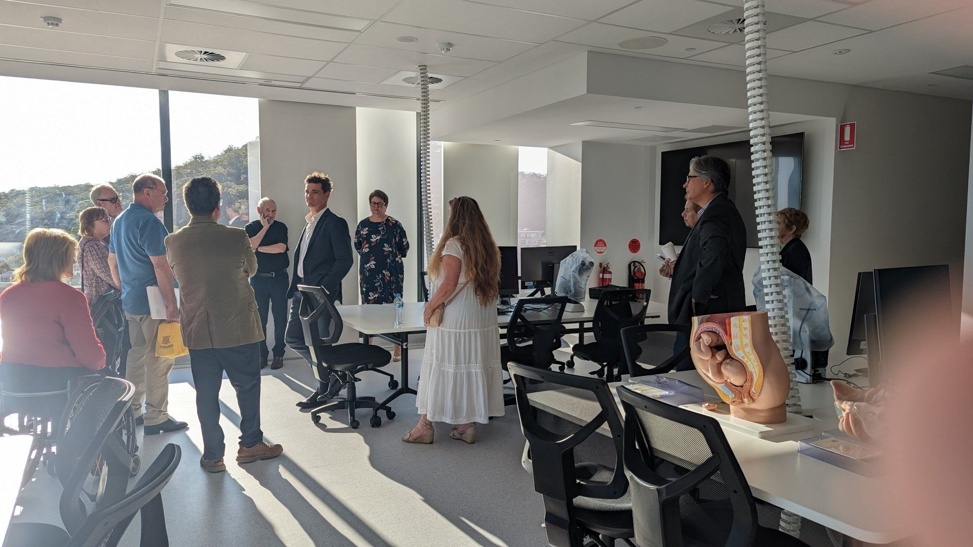A group of people are standing in an office talking to each other.
