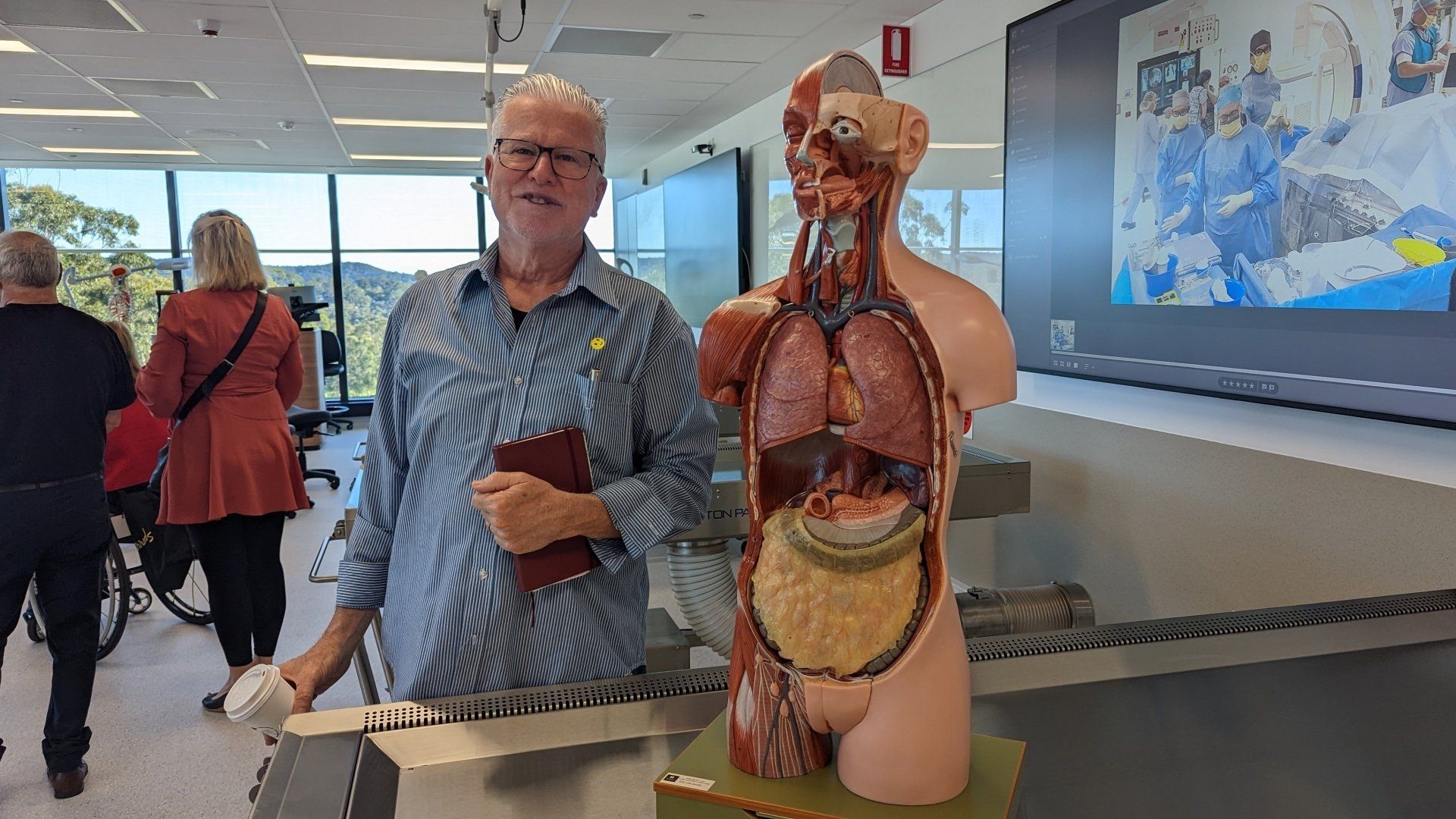 A man is standing next to a model of the human body.