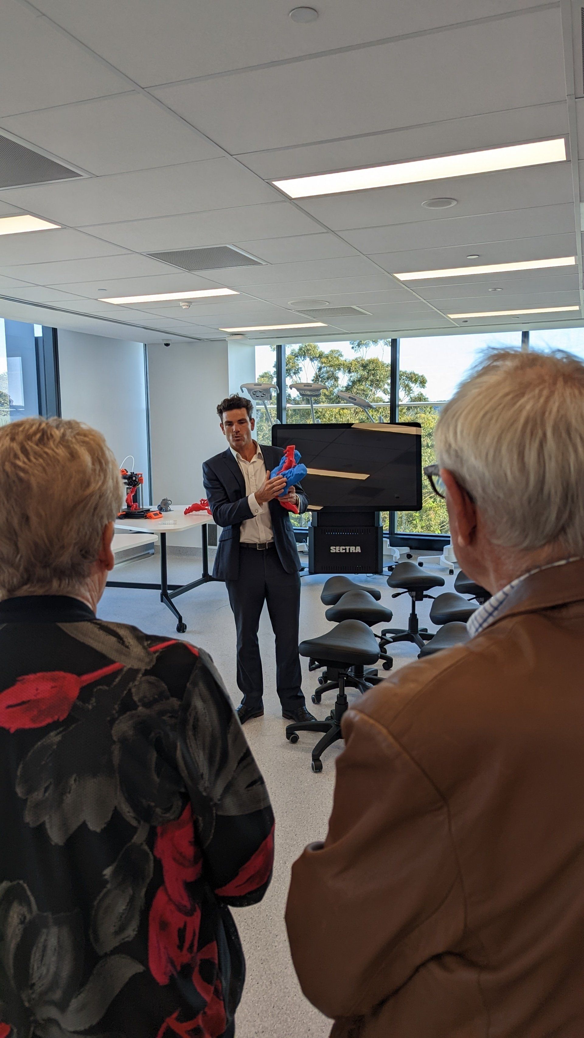 A man in a suit is giving a presentation to a group of people in a room.