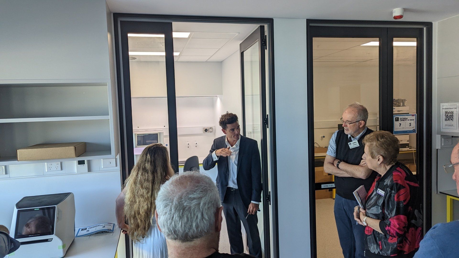 A group of people are standing in a room talking to each other.