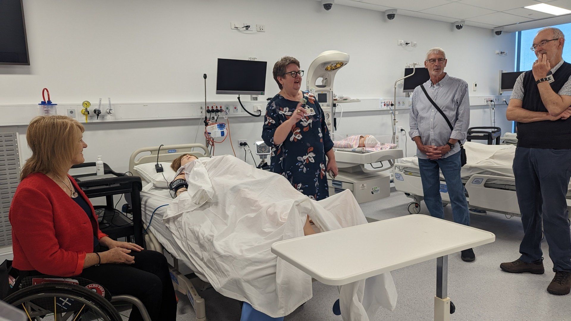 A group of people are standing around a hospital bed.