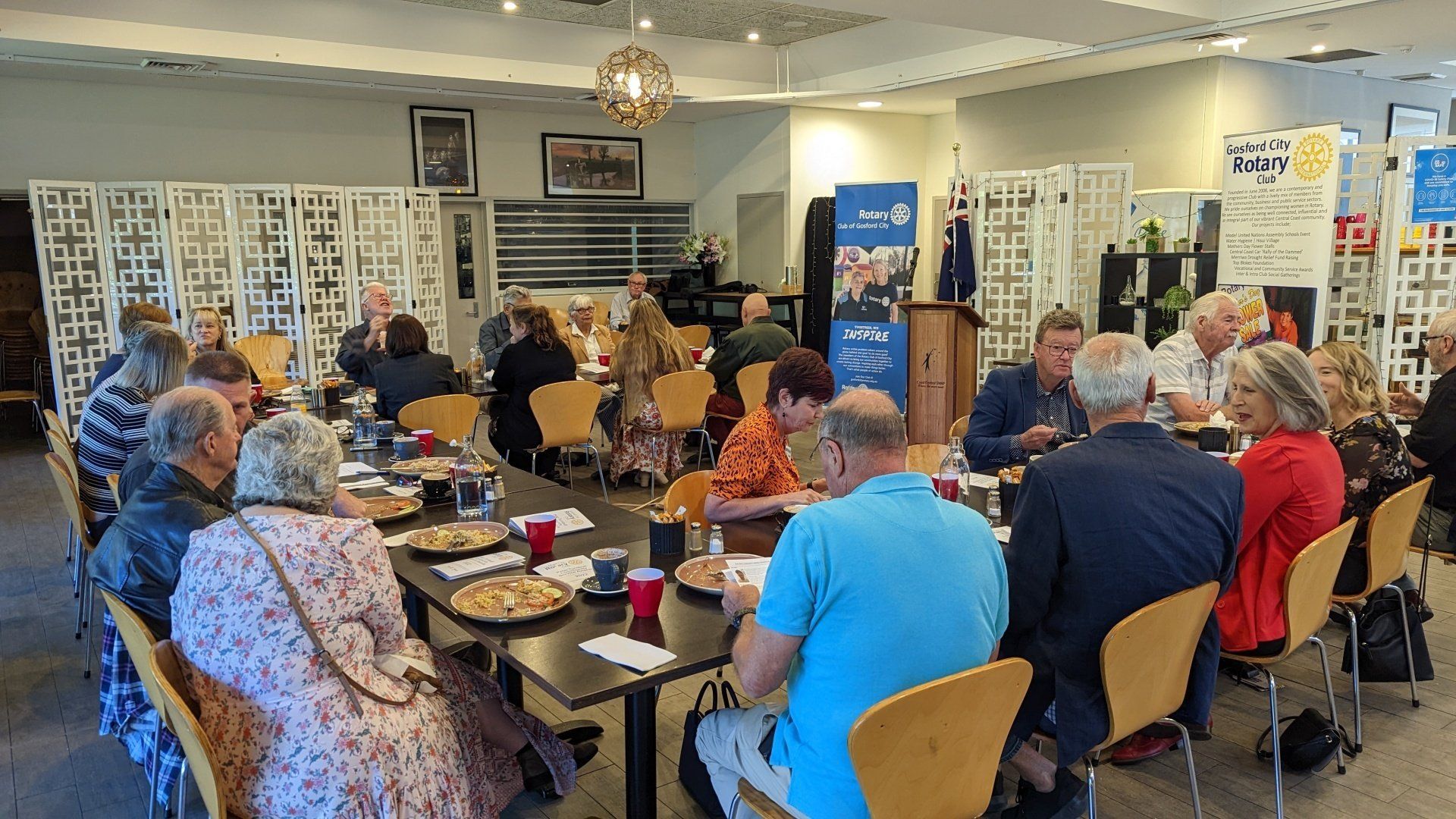 A group of people are sitting at tables in a room eating pizza.