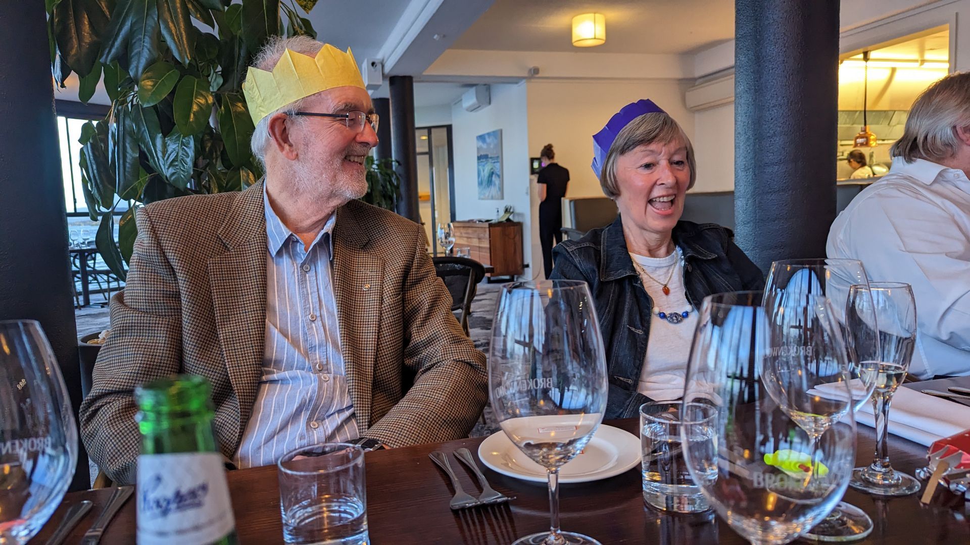 A man and a woman are sitting at a table with wine glasses.