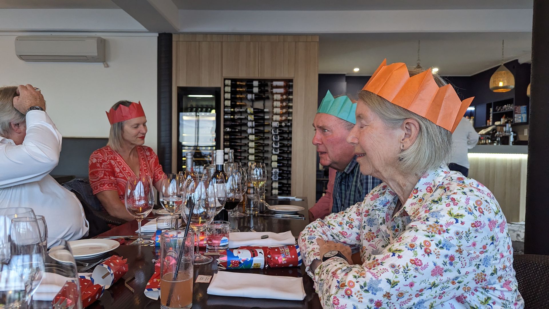 A group of people are sitting at a table wearing paper crowns.