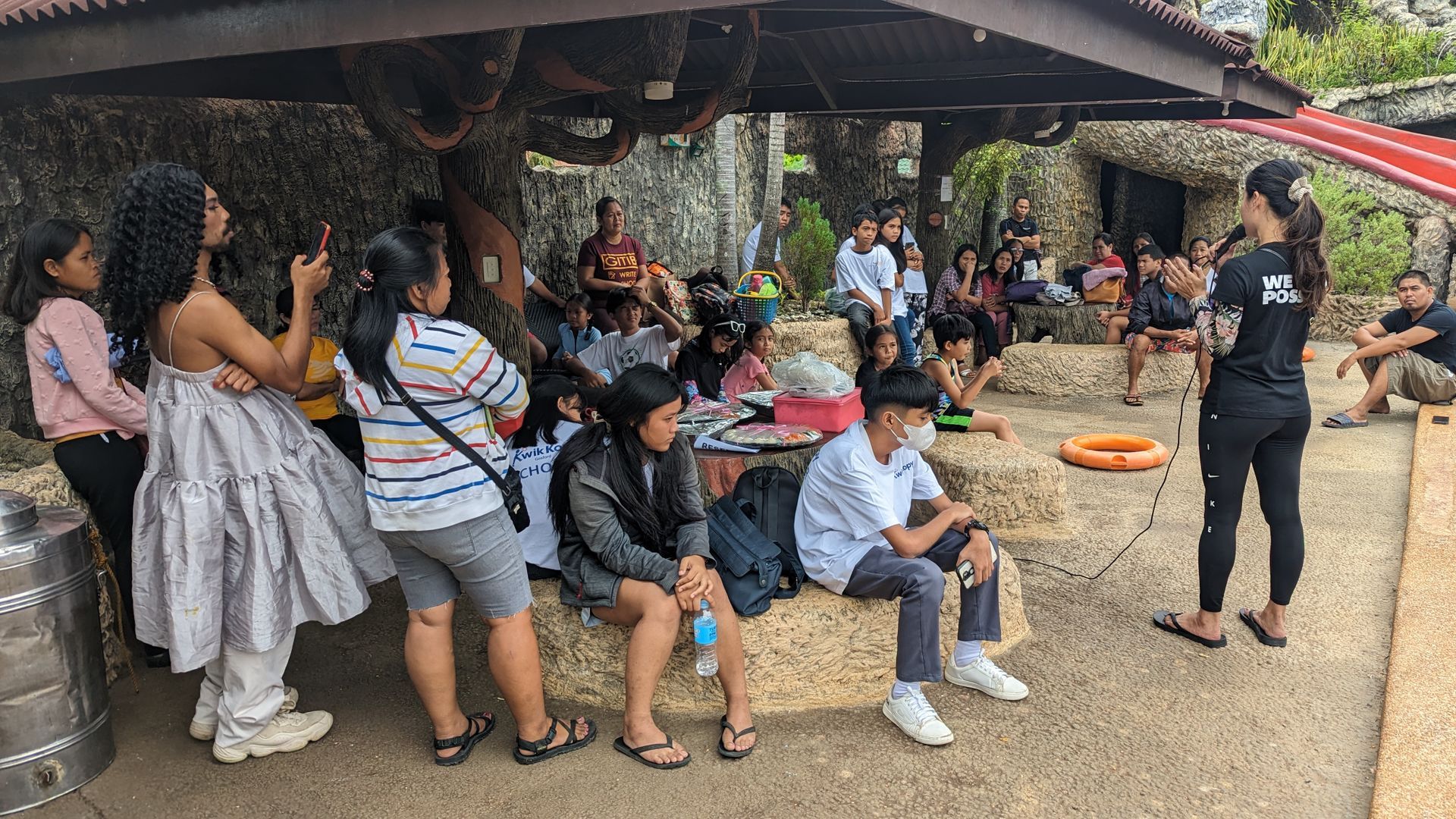 A group of people are sitting on benches under a pavilion.