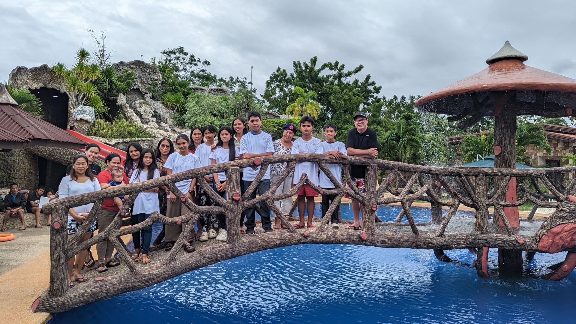 A group of people are standing on a bridge over a pool.