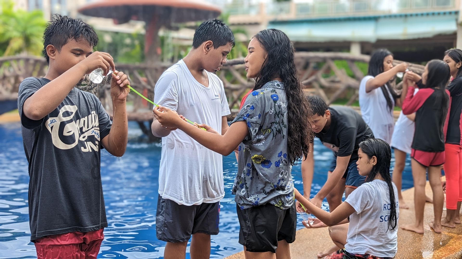 A group of people are standing next to a swimming pool.