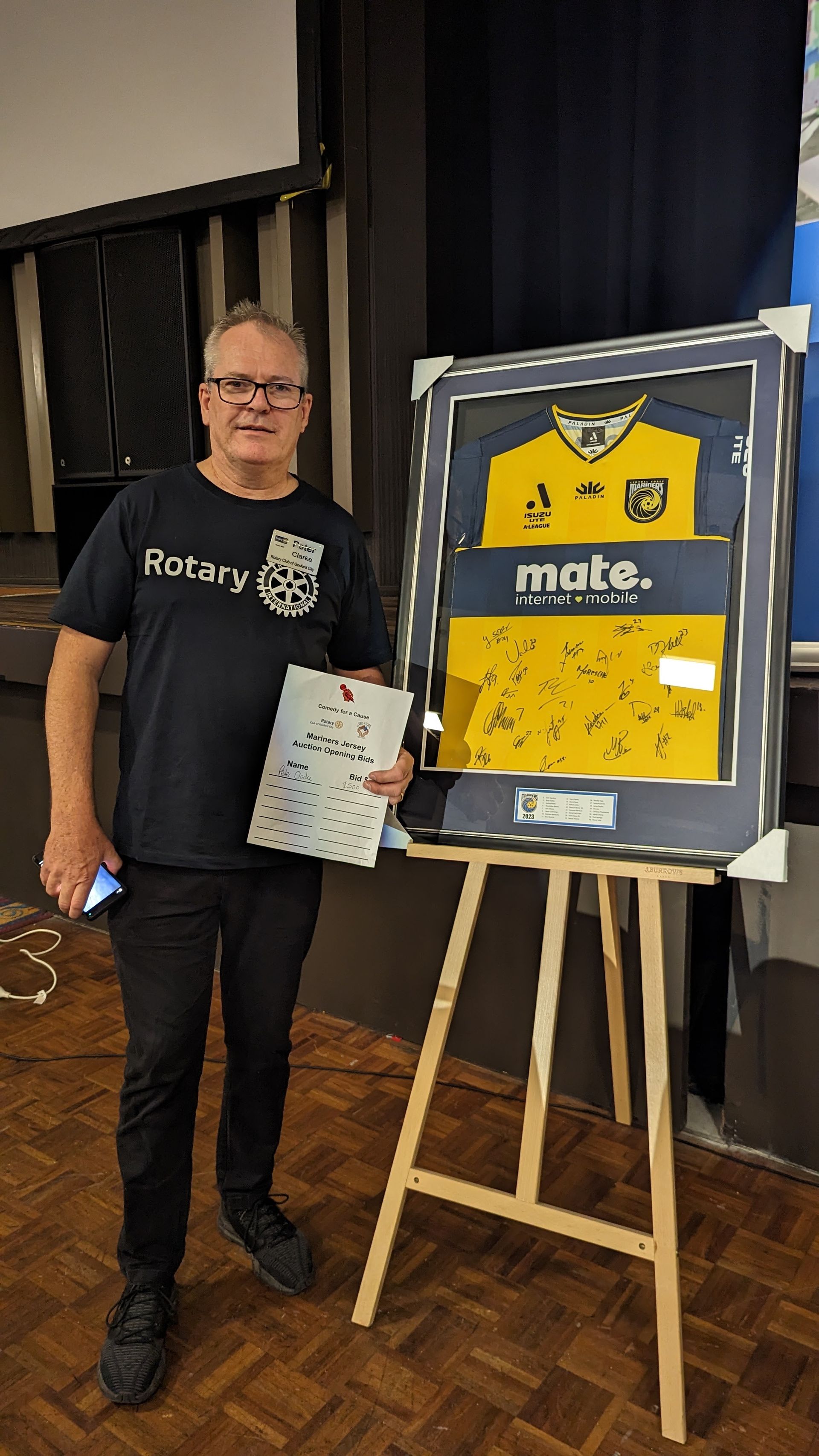 A man is standing in front of a framed jersey on an easel.