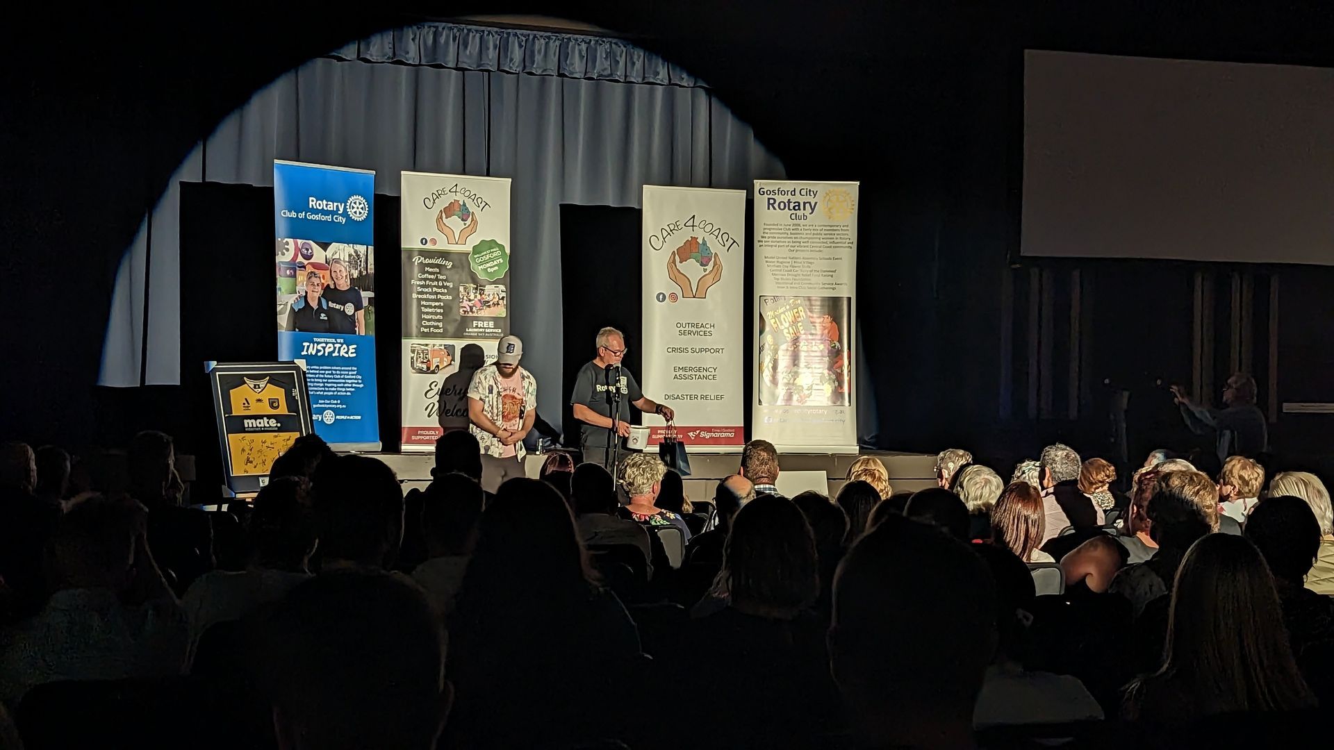 A man is standing on a stage in front of a crowd of people.