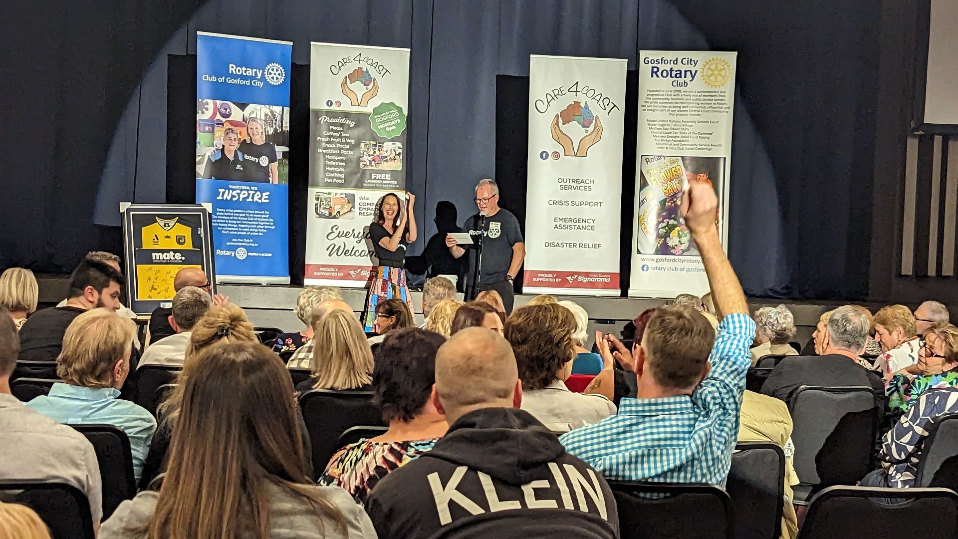 A group of people are sitting in a auditorium watching a presentation.