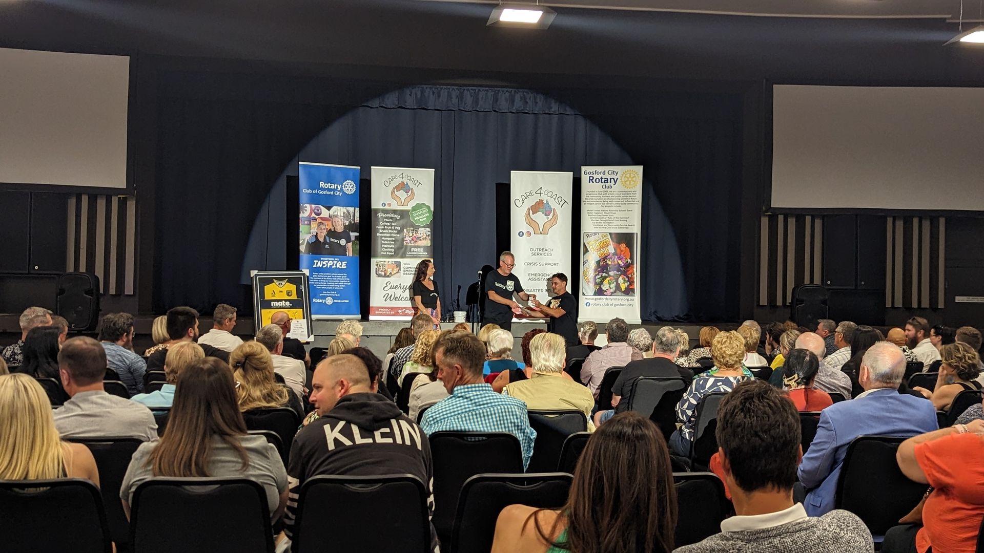 A large group of people are sitting in a auditorium watching a presentation.